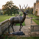 Life-Size Traditional Bull Elk Bronze Sculpture by Giant Sculptures with wide antlers and dark brown patina, displayed on a stone terrace beside a country estate.