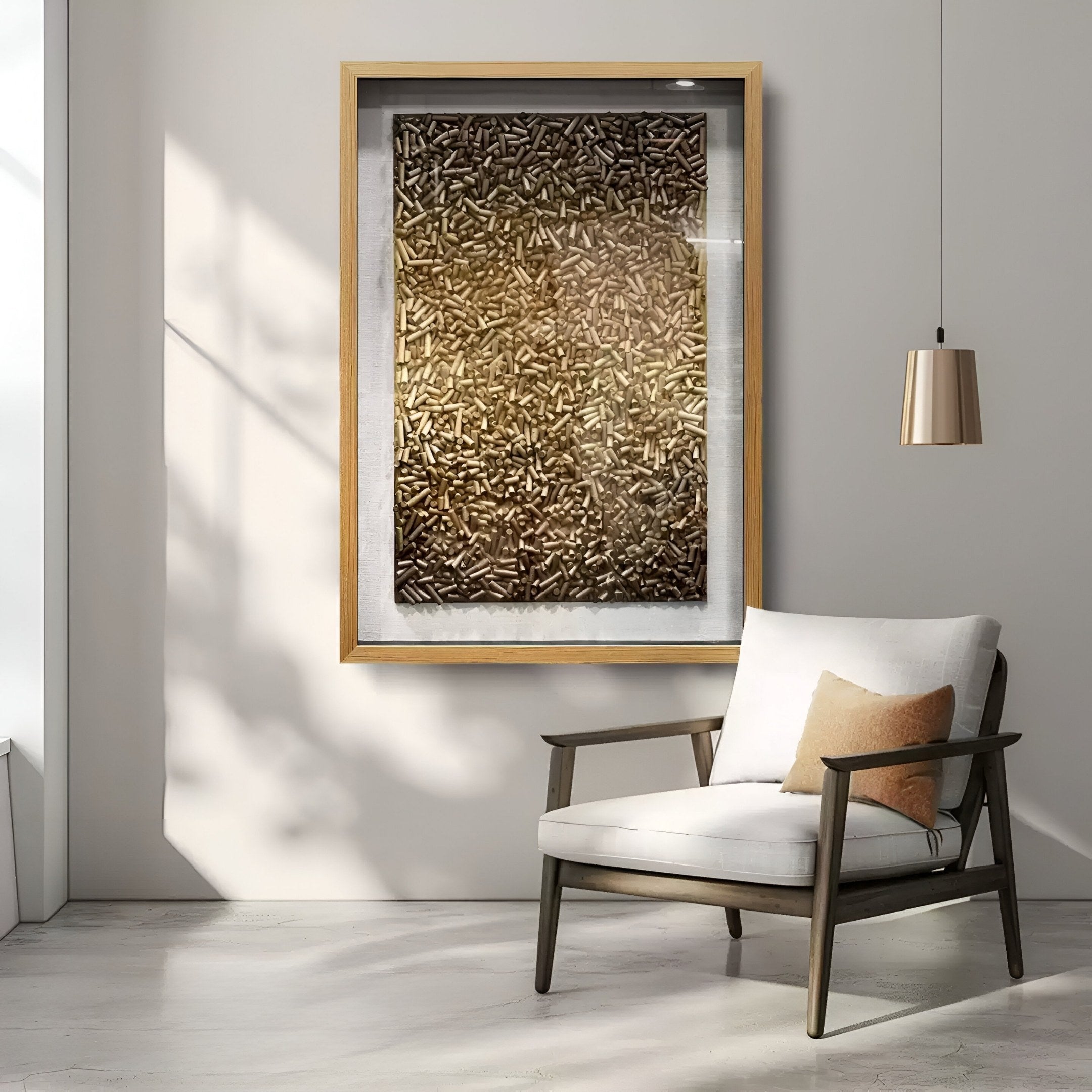 A modern living room features a light armchair with a tan pillow, a pendant light, and the Brivora Golden Bronze Gradient Textured 3D Wall Art by Giant Sculptures. Sunlight creates soft shadows in this neutral-toned space.