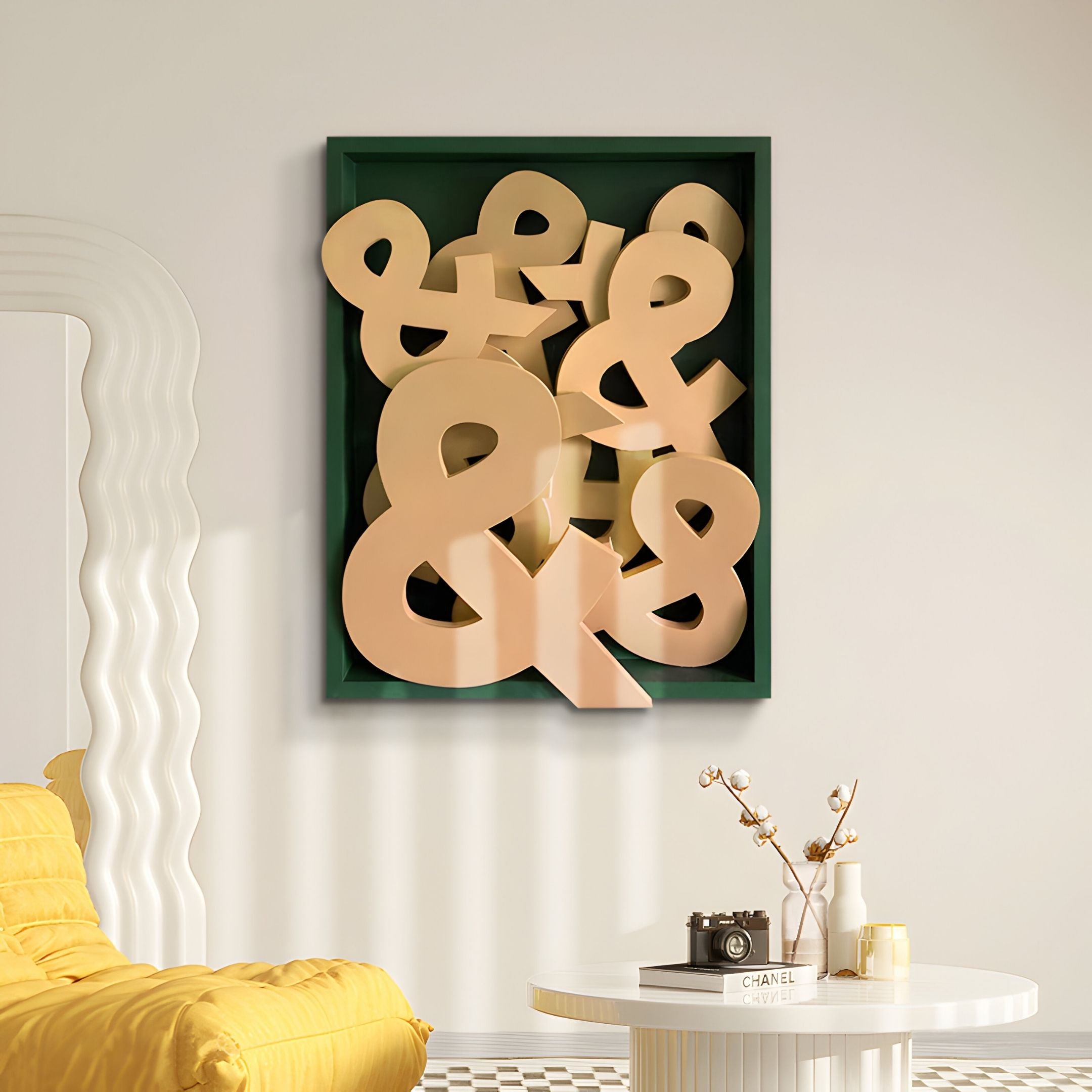 The Typova Mustard Ampersand Wood Carving 3D Wall Art by Giant Sculptures features overlapping beige ampersands, adding depth and modern style above a yellow chair beside a round white table with decor.