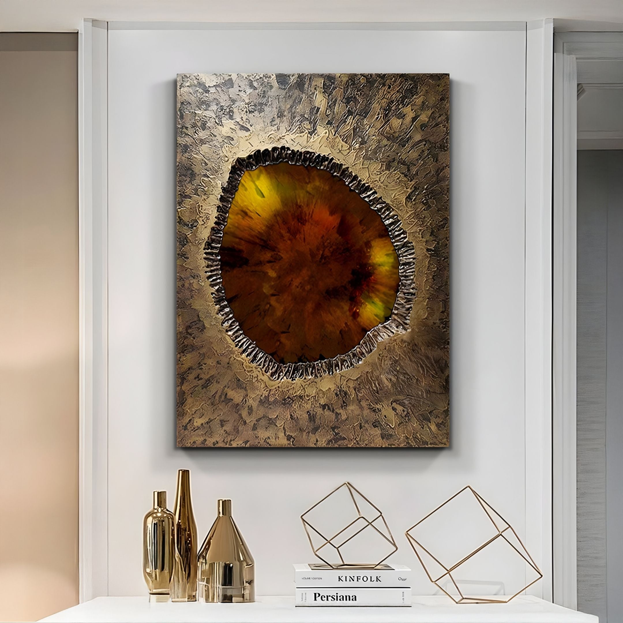 The Vorthera Ember Glow Textured Gold 3D Wall Art by Giant Sculptures, with its earthy brown, orange, and yellow circular design, is displayed above a white console table decorated with gold vases, geometric sculptures, and stacked books.