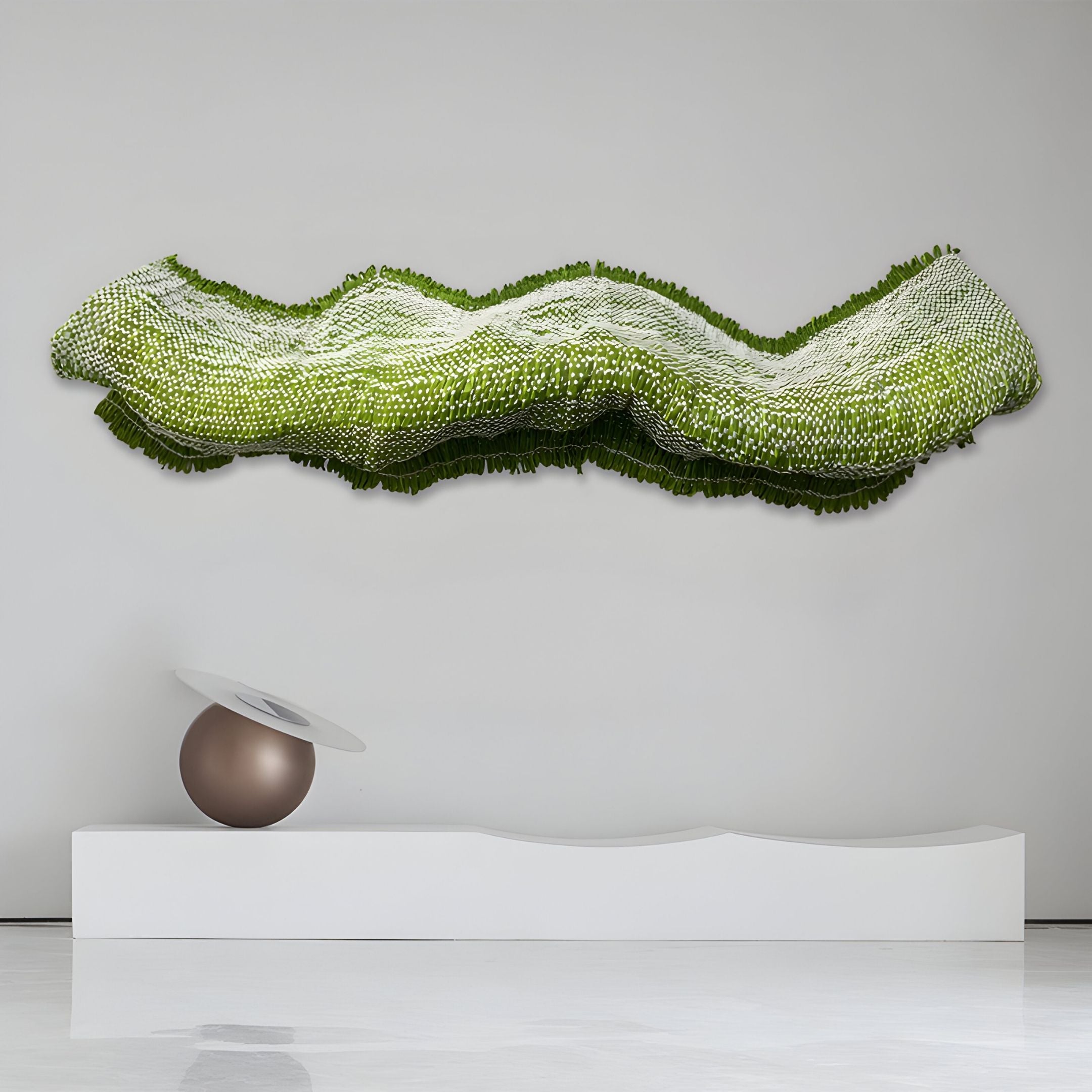The Lyronda Green Textured Woven 3D Wall Art by Giant Sculptures features a wavy, sculptural design on a white wall, complemented by a metallic sphere and tilted white disc displayed on a curved platform below.