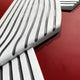 Close-up of a stylized silver and black emblem with curved lines on a shiny red background, evocative of Giant Sculptures’ Arcluma Crimson Stripe Fold Leather 3D Wall Art.