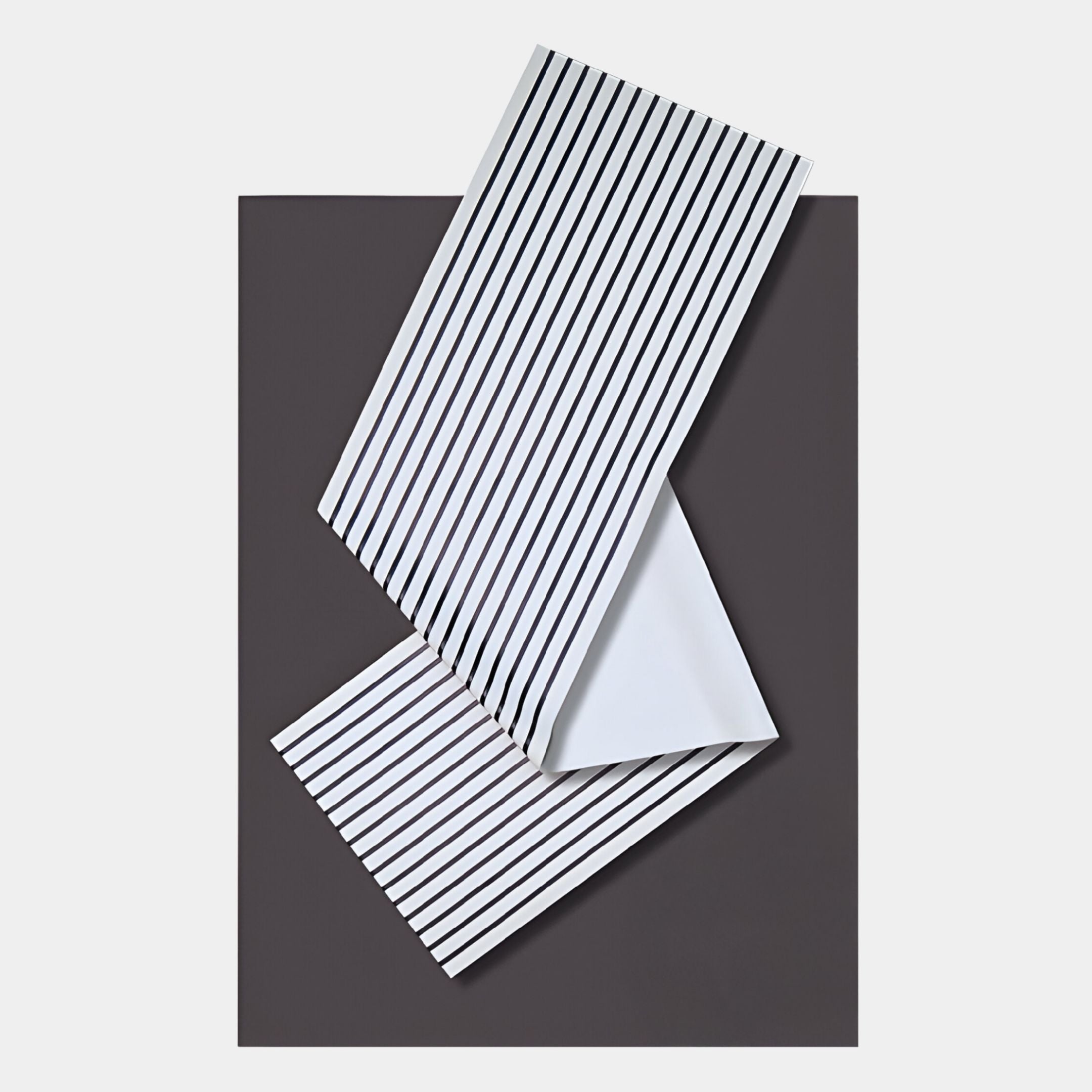 The Arcluma Charcoal Stripe Fold Leather 3D Wall Art by Giant Sculptures features a folded sheet design with black stripes on white leather, set against a dark gray backdrop for a sleek, modern geometric accent.