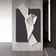 The Arcluma Charcoal Folded Ribbon Leather 3D Wall Art by Giant Sculptures features white, ribbed, folded shapes on a dark background, displayed on a textured light gray wall in a minimalist setting.