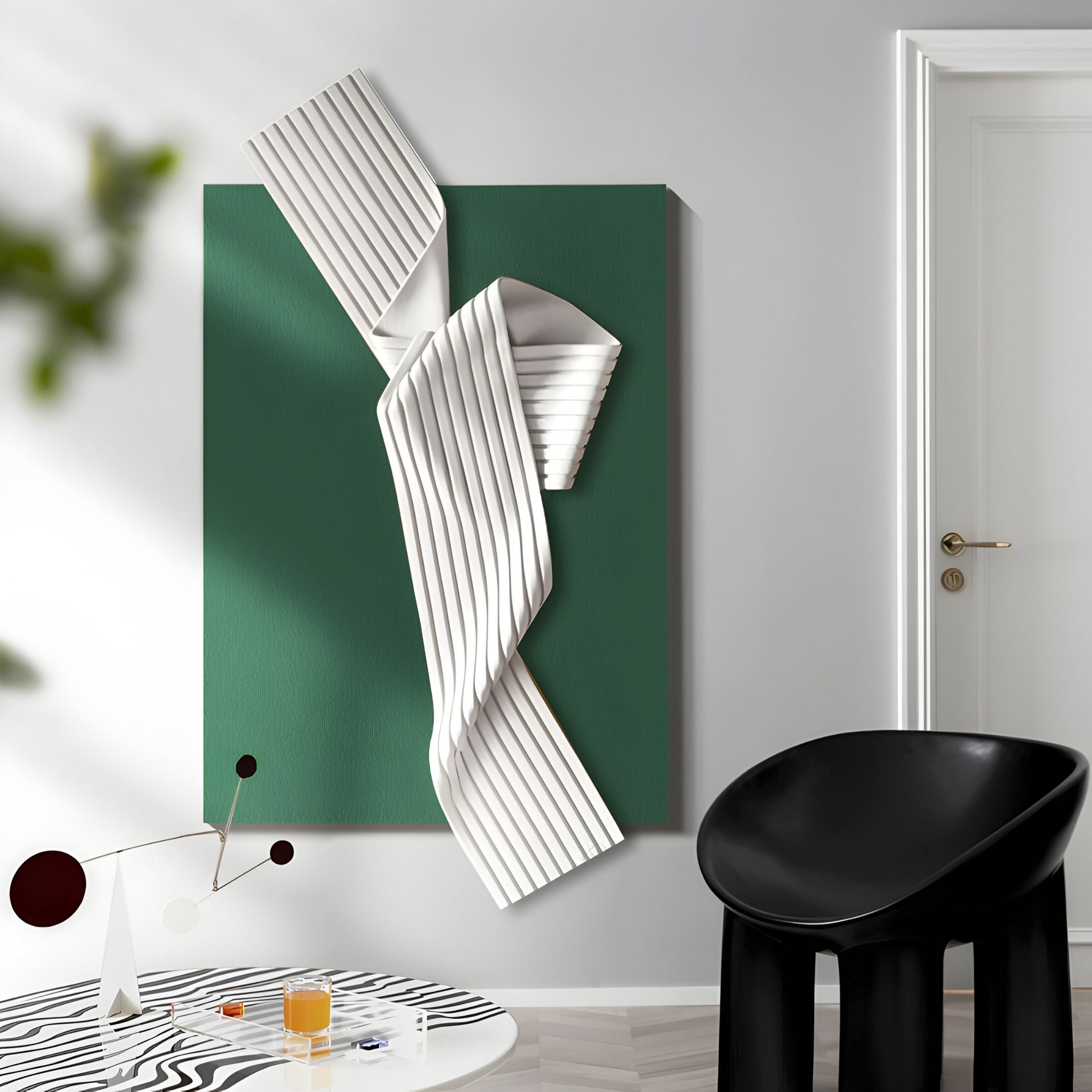 A modern interior with Giant Sculptures’ Arcluma Forest Green Folded Ribbon Leather 3D Wall Art, a black chair, a white round table with a black pattern, and a minimal mobile sculpture.