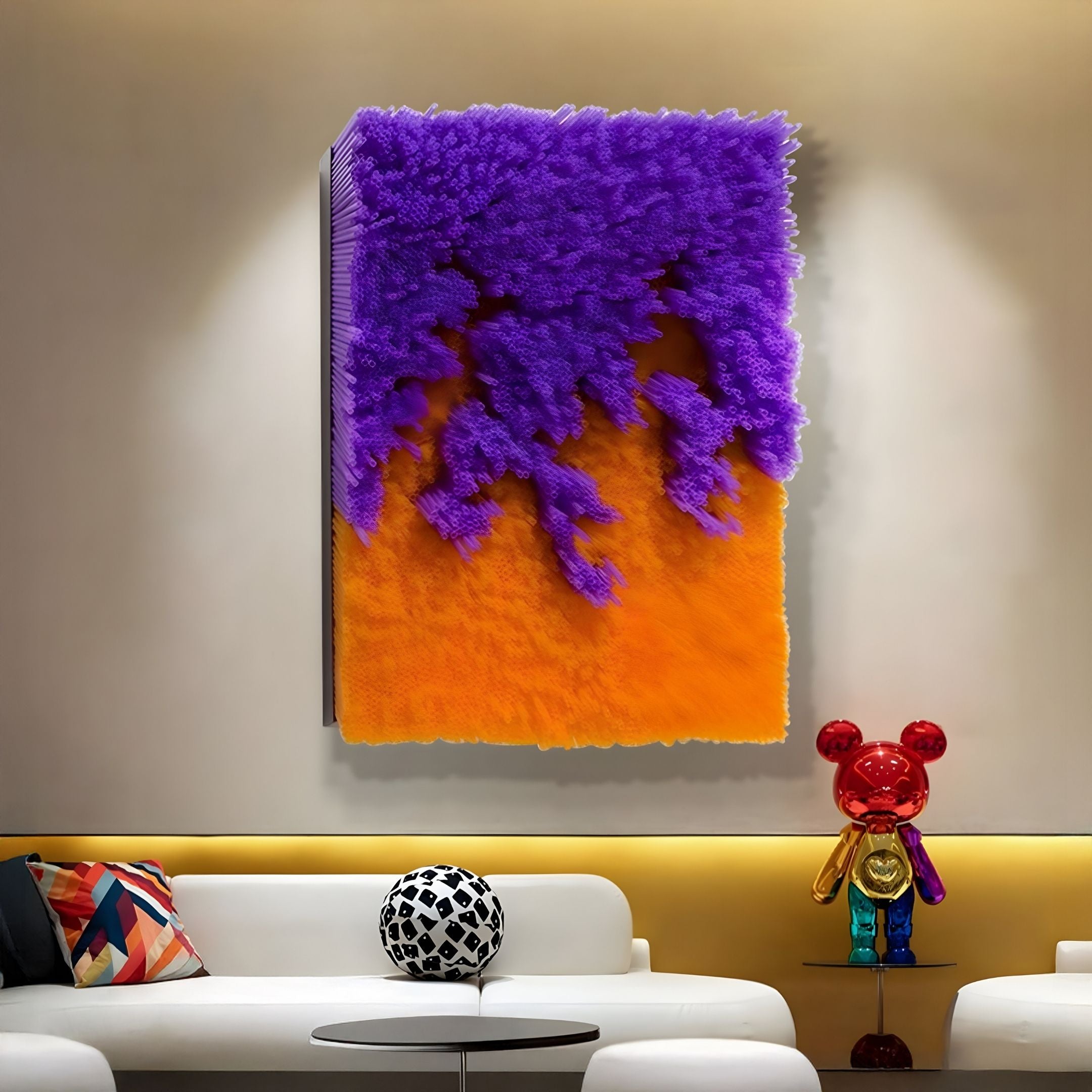 A modern living room features a white sofa, colorful pillows, and a round black-and-white cushion. Above a shiny red bear sculpture, Giant Sculptures’ Chromavolt Violet & Amber Straw 3D Wall Art adds bold flair to the contemporary space.