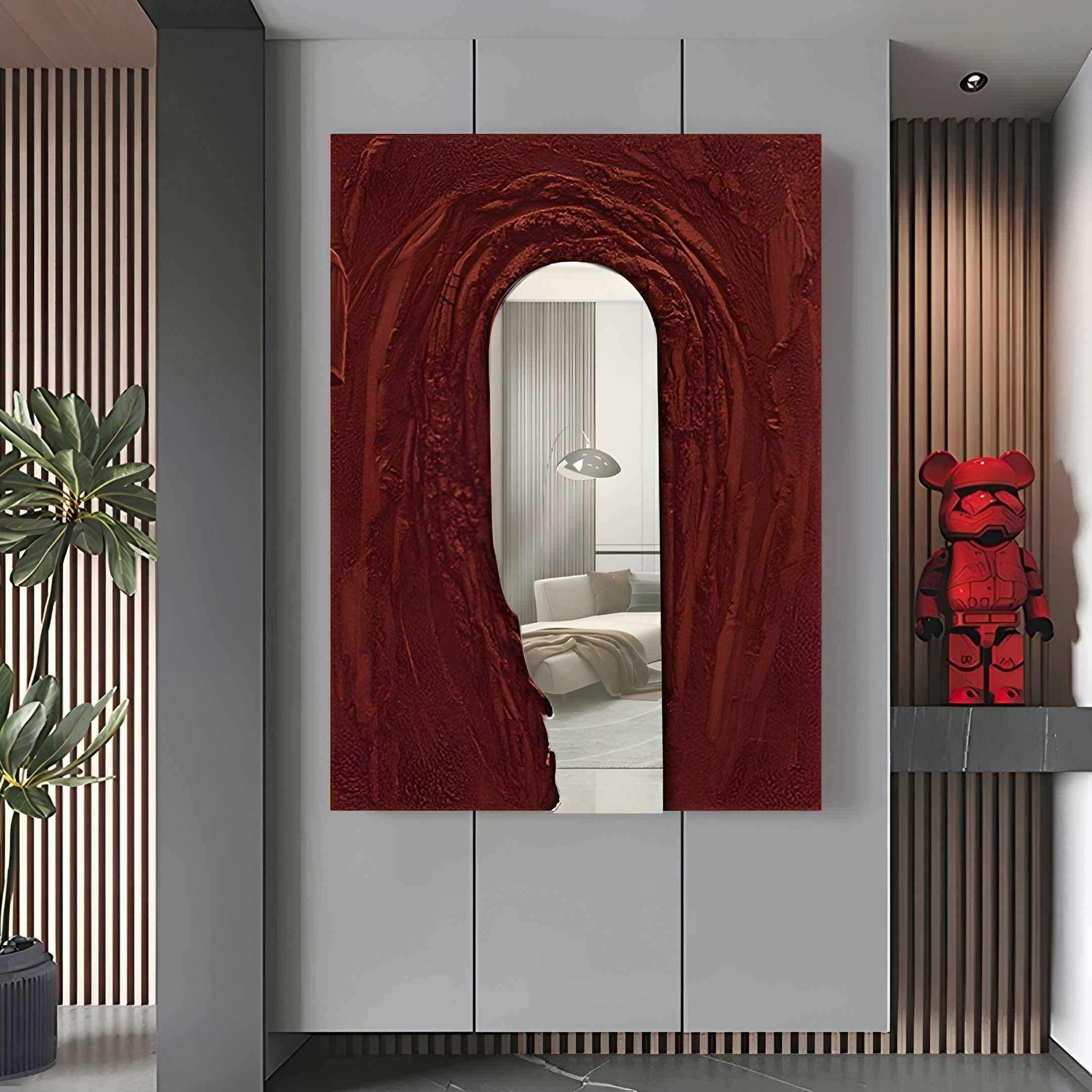 A modern hallway features the Arclunor Merlot Red Arch Relief Mirror 3D Wall Art by Giant Sculptures reflecting a cozy room, with a red bear figurine on the right, a tall green plant on the left, and vertical wood panels accenting the luxury decor.