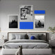 A modern bedroom features a neatly made bed in grey tones, with Giant Sculptures’ Framegrid Blue Mixed-Size Gallery 5-Set Acrylic Wall Art above the headboard. A gray cat sculpture at the foot of the bed completes the minimalist decor.