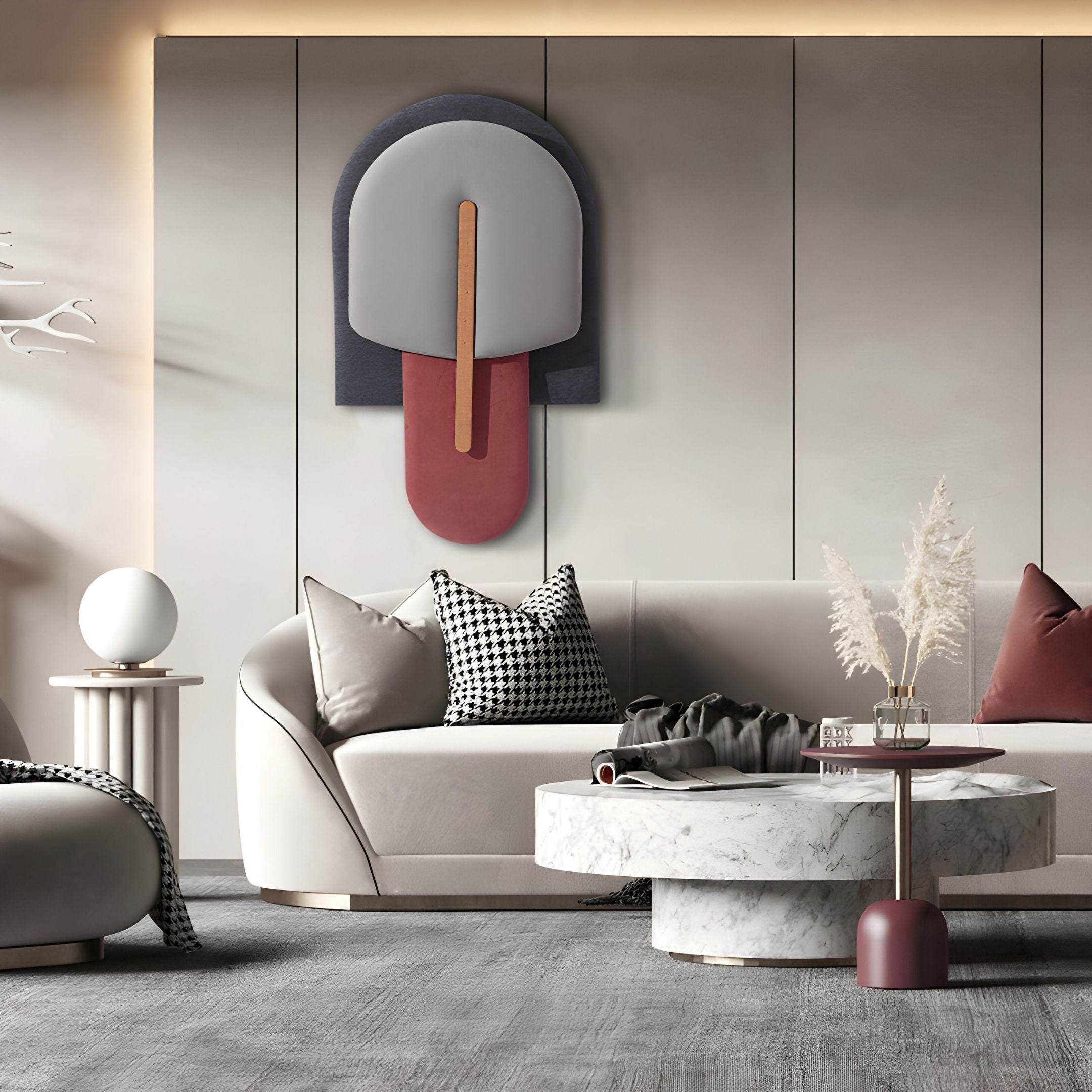 A modern living room with a curved beige sofa, patterned pillows, a round marble coffee table, pampas grass in a vase, and Giant Sculptures' Solvia Grey & Burgundy Layered Geometry 3D Wall Art. The décor is minimalist and stylish.