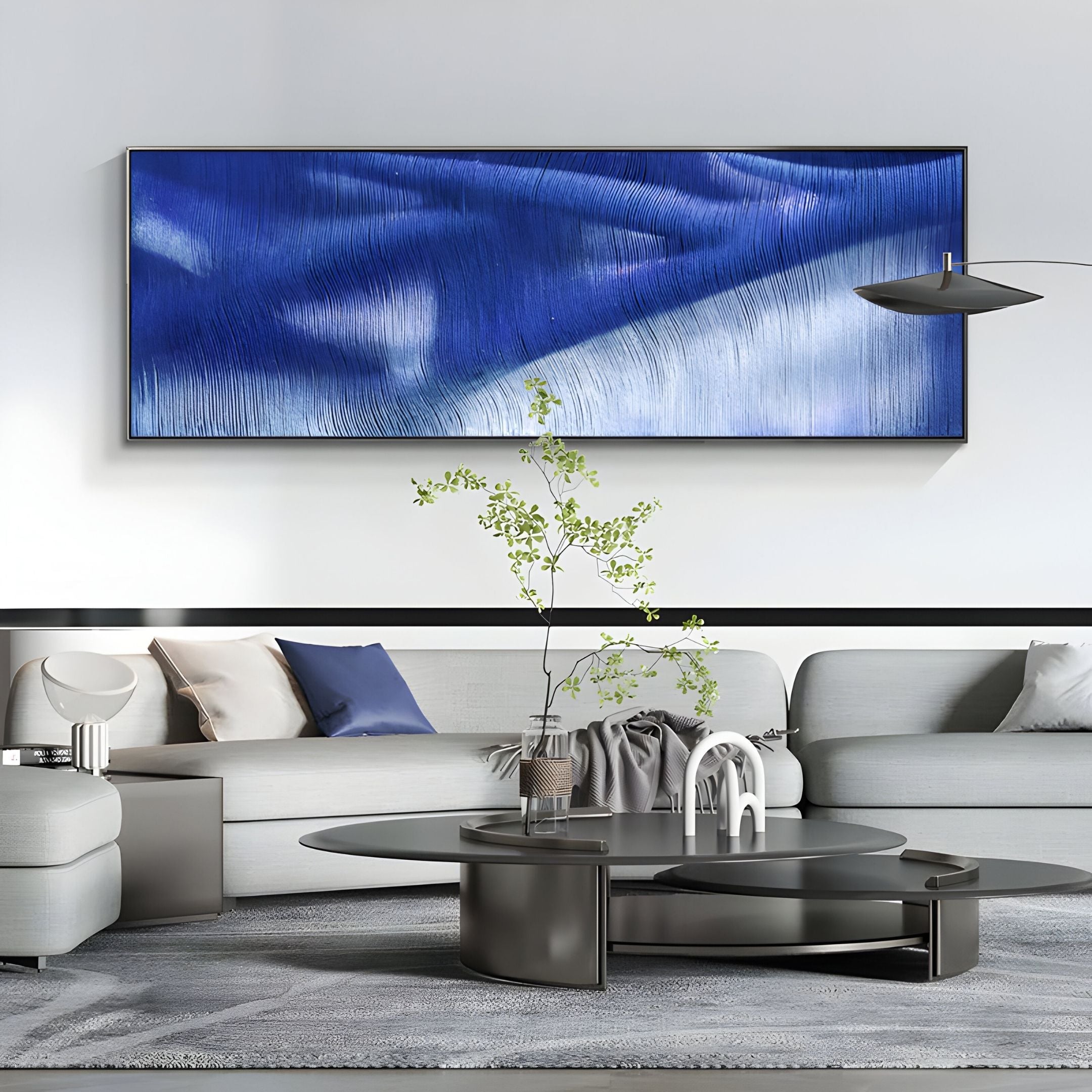A modern living room with light gray sofas, a round black coffee table, and the Rivara Cobalt Wave Vertical Hand-Painted Rope 3D Wall Art by Giant Sculptures creates a unique focal point in this stylish interior.