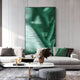 A modern living room features a light gray sofa, green and black cushions, a white coffee table with decor, and the Giant Sculptures Rivara Emerald Flow Hand-Painted Rope 3D Wall Art. The space is bright with elegant minimalist contemporary style.