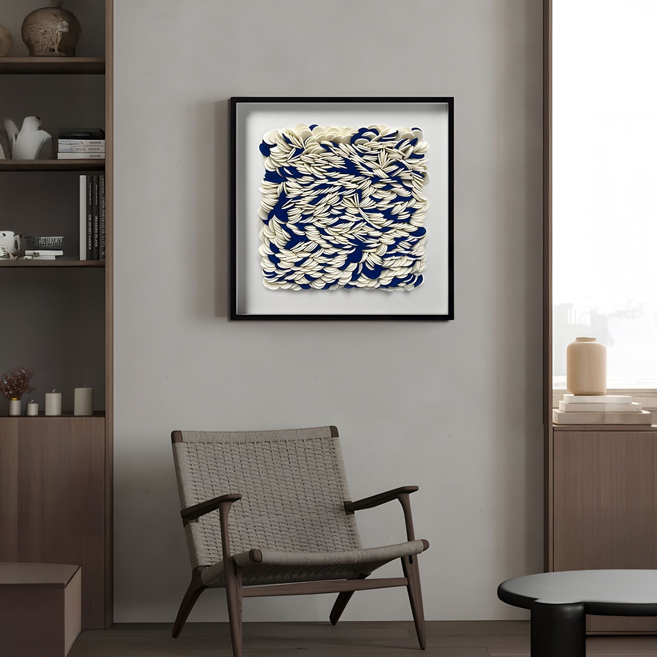 A modern living room with a woven armchair, neutral decor, and Giant Sculptures' Petalus Blue & Cream Layered Felt 3D Wall Art on a gray wall. Books and vases on shelves complete these striking contemporary interiors.