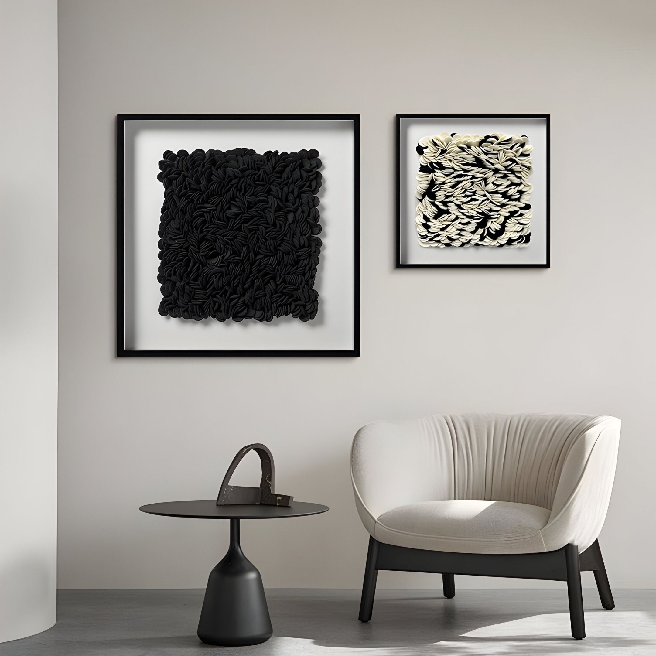 A modern minimalist room with a white armchair, small black side table, and striking Petalus Black Layered Felt 3D Wall Art by Giant Sculptures hanging on a light gray wall.