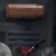 The Vintor Gentleman Pipe, Cigar & Heritage Framed Wall Art by Giant Sculptures features a brown leather case above a red and black curved pipe on a dark surface, with a person's shoulder visible, evoking vintage-inspired style.