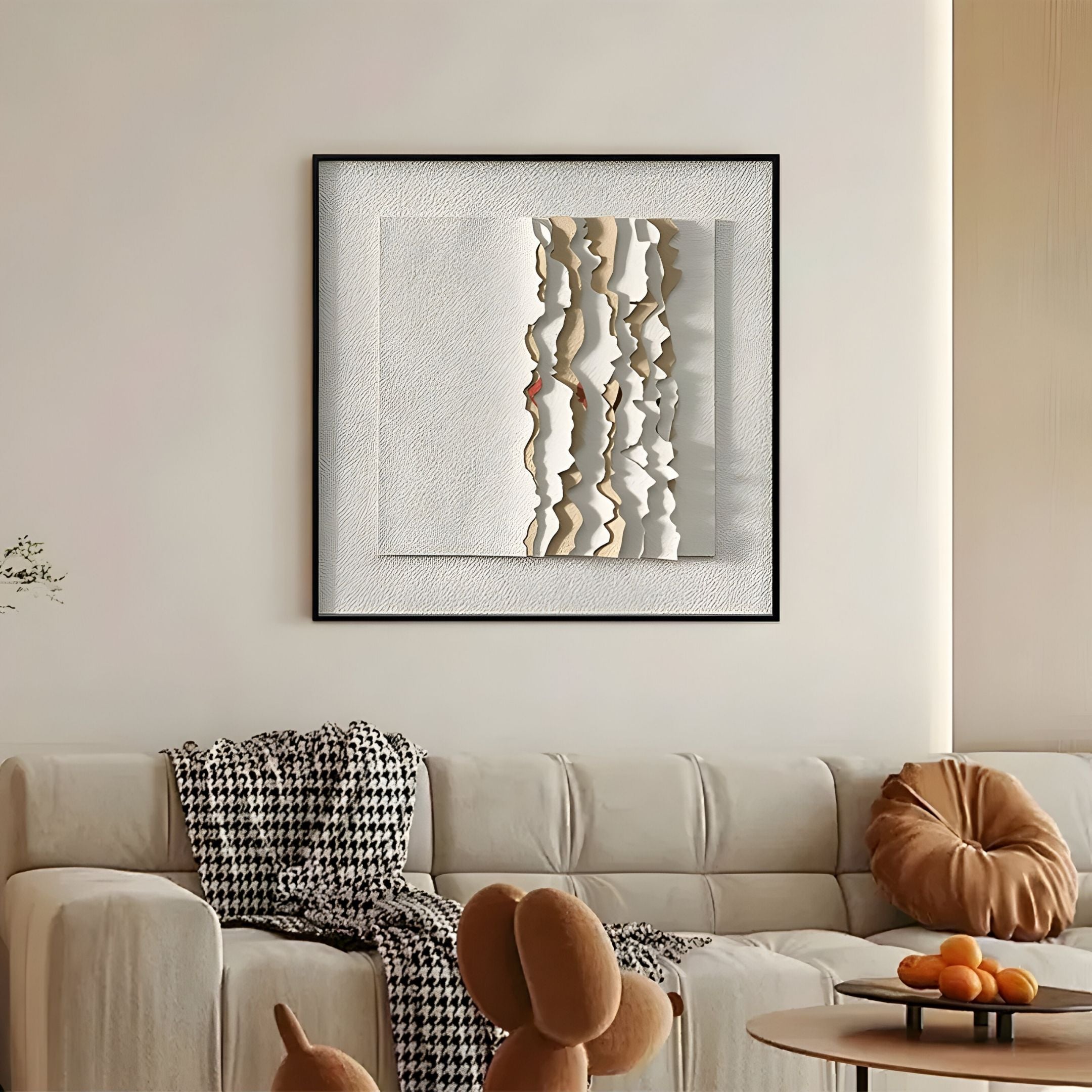 A modern living room with a beige sofa, houndstooth throw, and round cushion. "Rivura White Layered Sandstone Texture 3D Wall Art" by Giant Sculptures hangs on the wall. A coffee table displays a sculpture and a bowl of oranges.