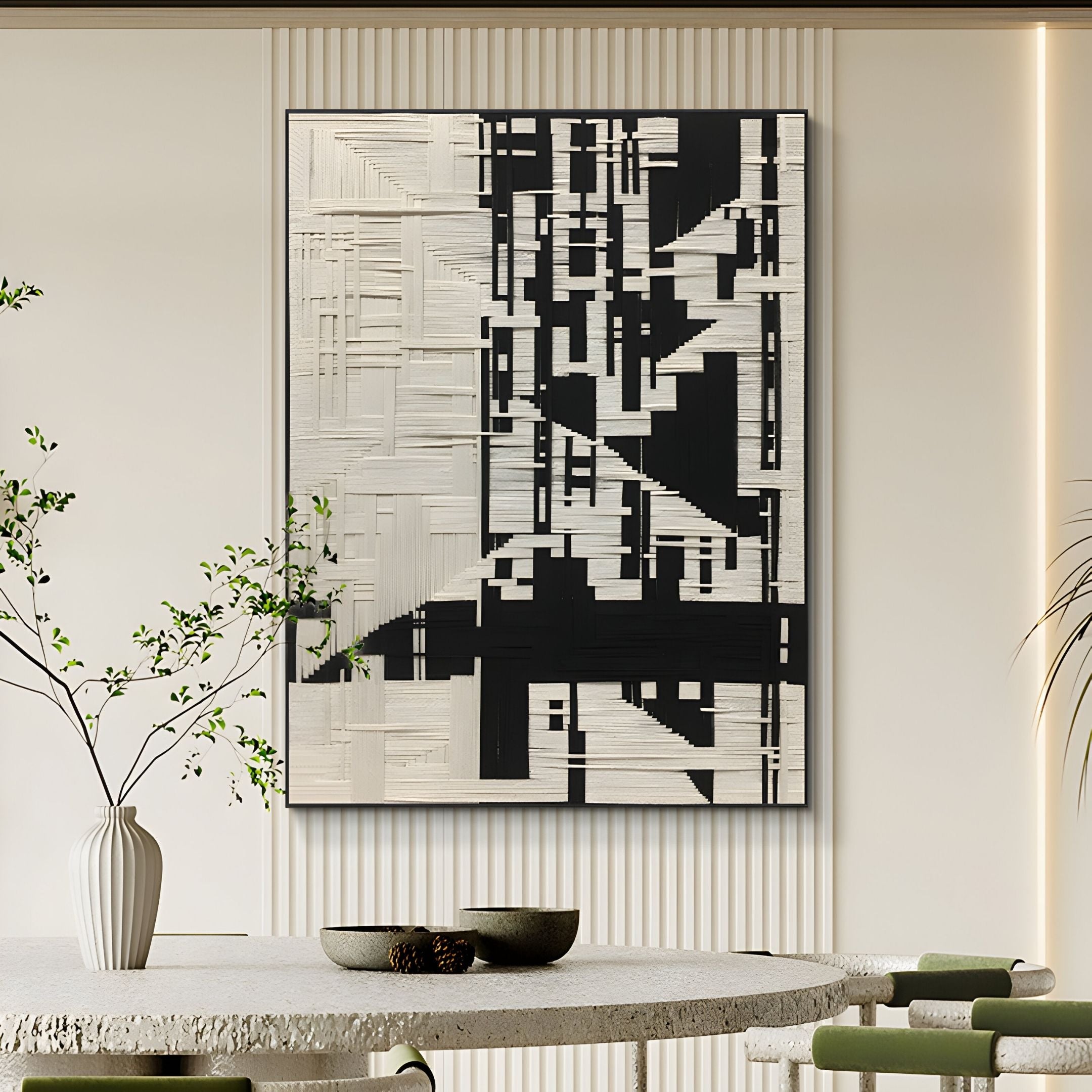 The Lintrix Black & White Geometric Woollen Knit 3D Wall Art by Giant Sculptures hangs on a cream wall in a modern, minimalist room, with a round table featuring green plants and ceramic bowls in the foreground.
