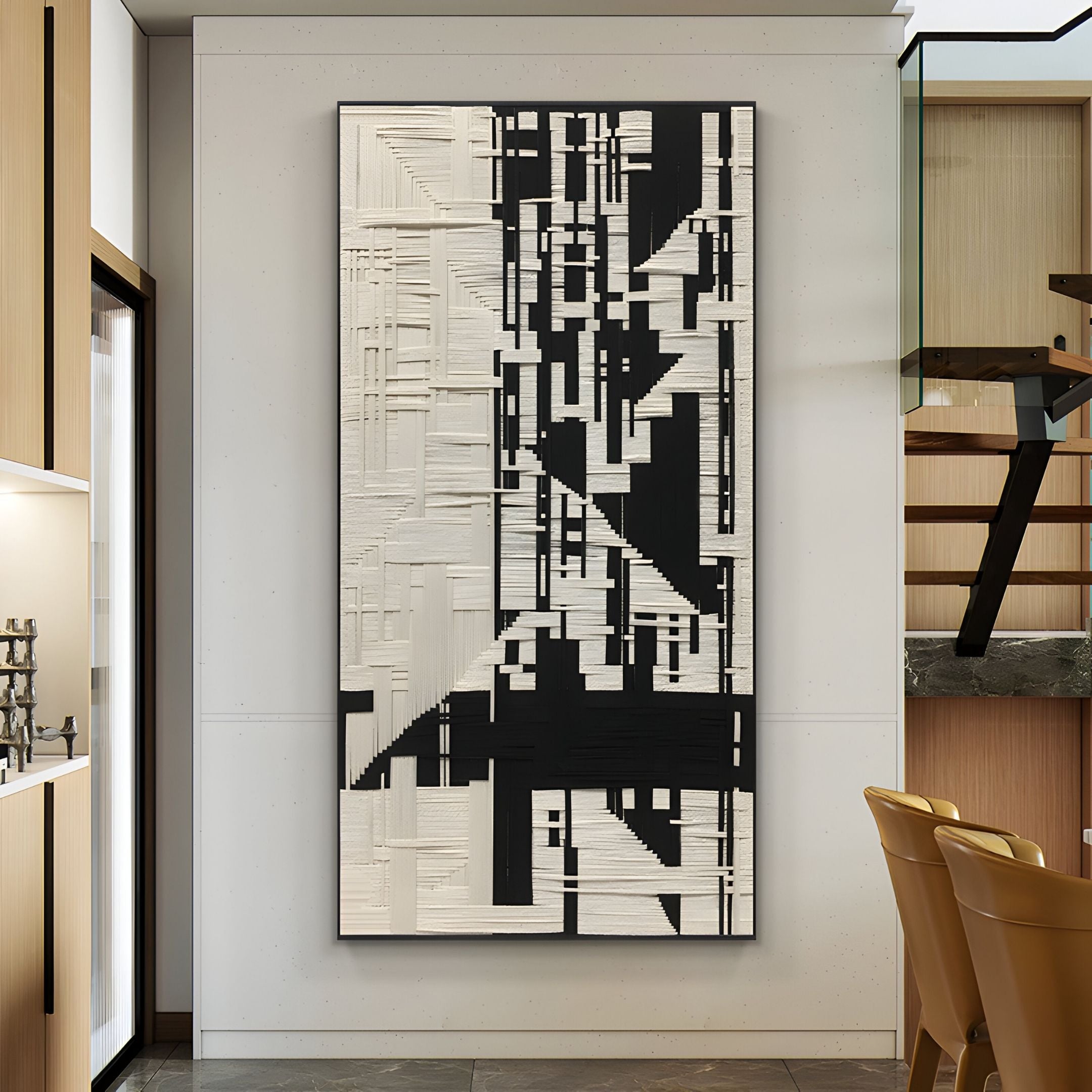 The Lintrix Tall Black & White Geometric Woollen Knit 3D Wall Art by Giant Sculptures hangs on a white wall in a modern space with wood and metal accents and tan chairs nearby.