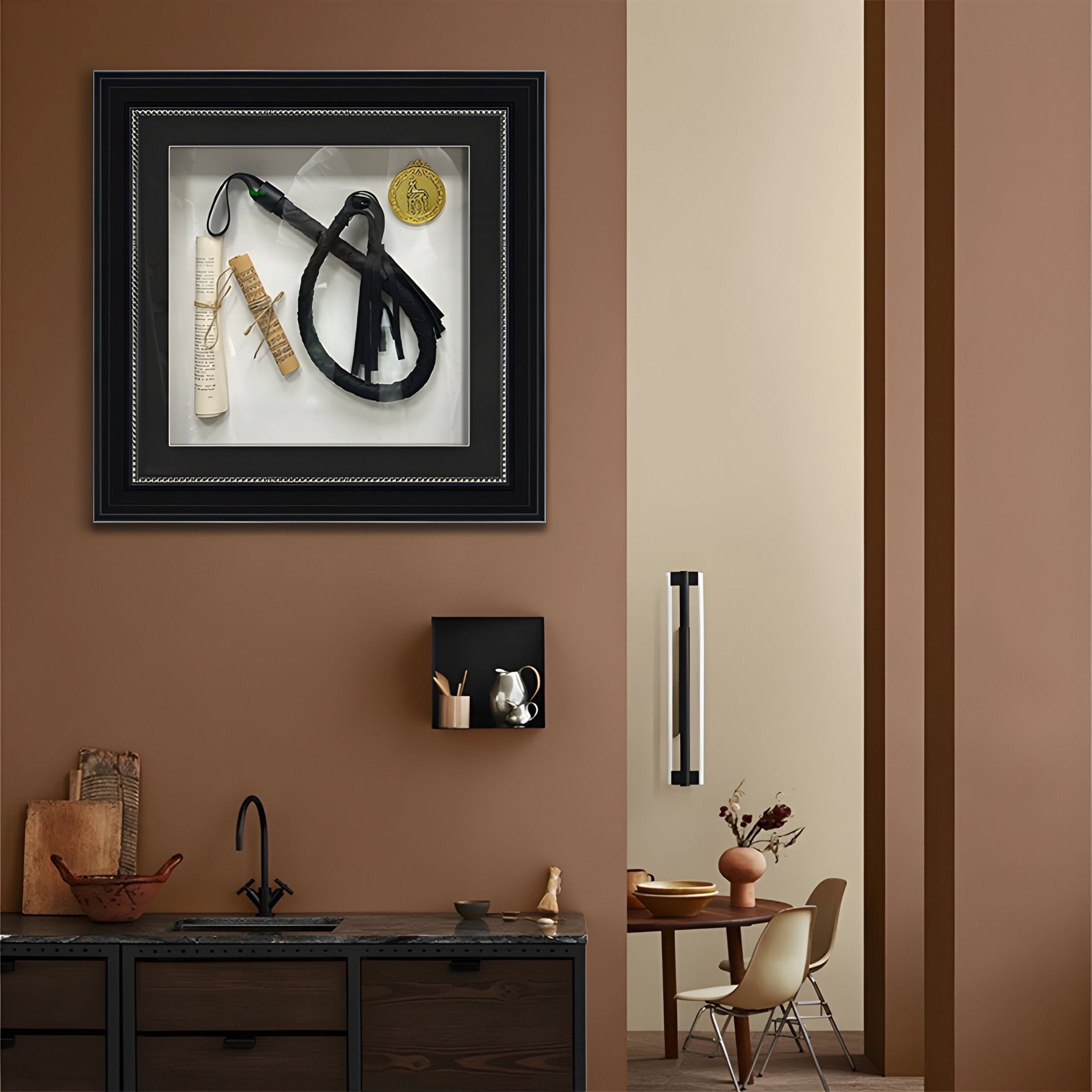 A modern kitchen with brown walls showcases the Prestivo Whip & Scroll Framed Collectible Wall Art by Giant Sculptures, featuring horse grooming tools and a ribbon, mounted above a counter with a sink, shelves, and minimalist decor.
