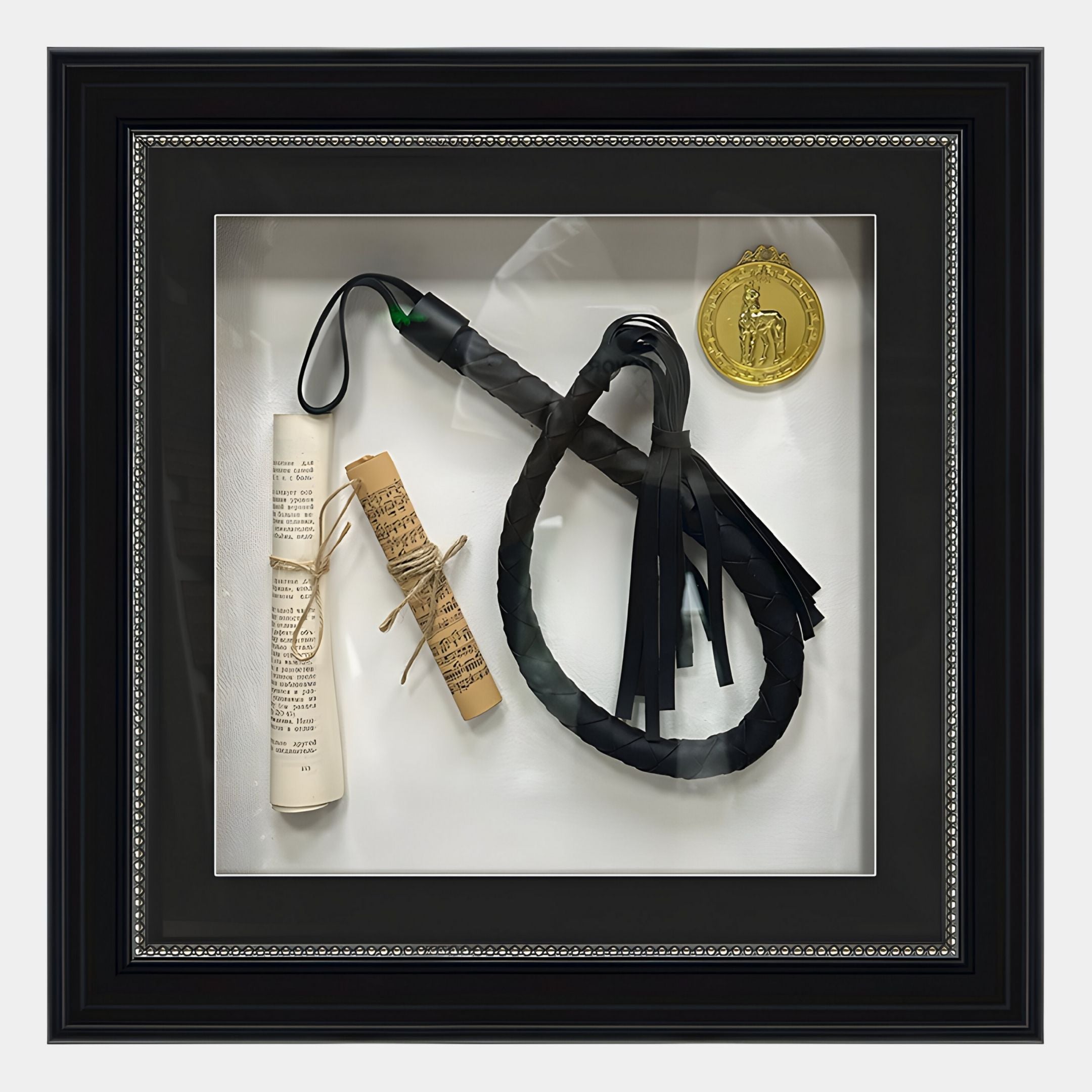 The Prestivo Whip & Scroll Framed Collectible Wall Art by Giant Sculptures displays a coiled black leather whip, two tied scrolls, and a gold horse medallion against a neutral backdrop.