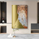 The Aurivara Gold Metal & Earth Textured Abstract 3D Wall Art by Giant Sculptures hangs on a beige wall above a dark console, while a minimalist table with a vase and green branch complements the contemporary decor.