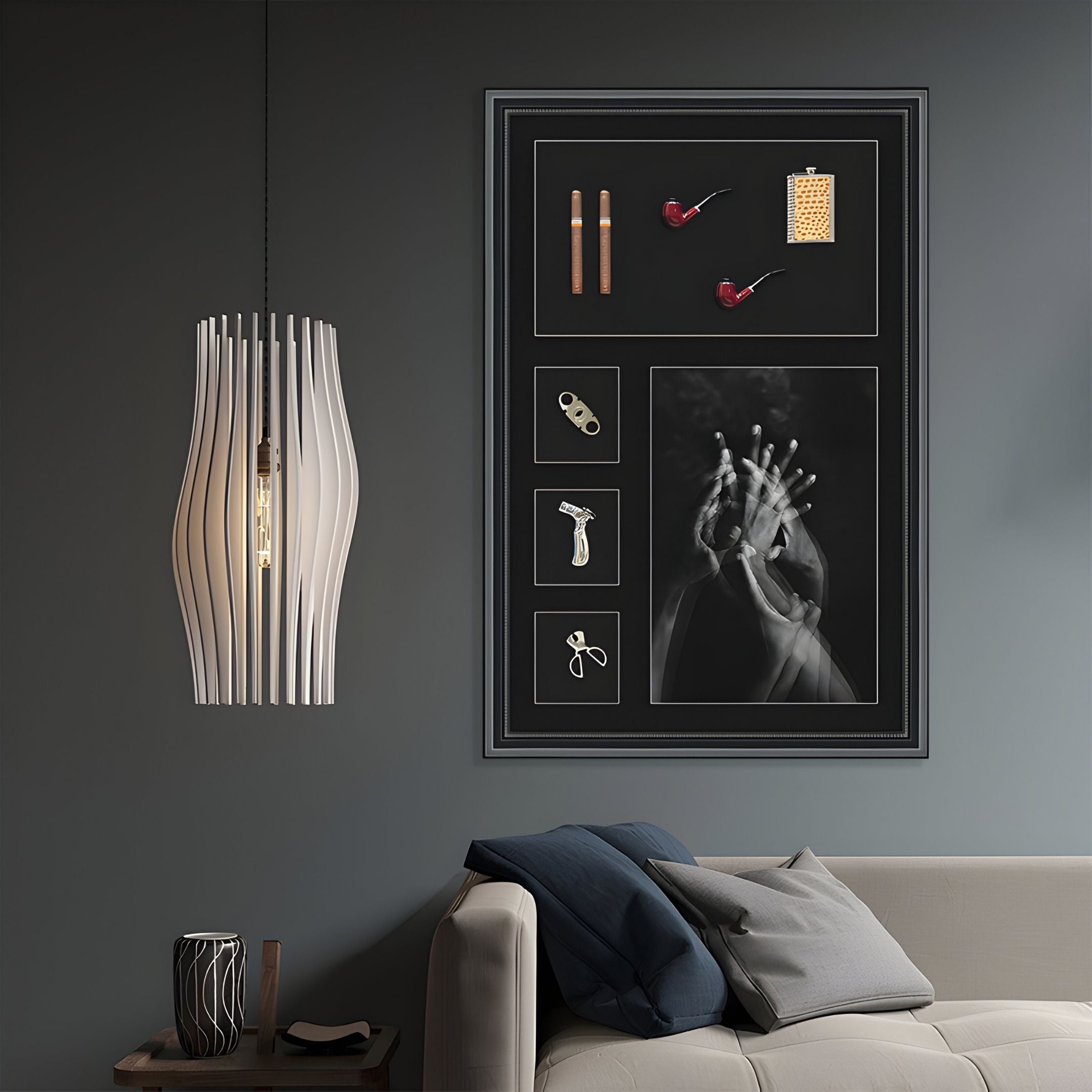 A modern living room with a white sofa, blue and gray cushions, a unique white pendant lamp, and Curatoria Cigar & Hand Study Framed Wall Art by Giant Sculptures featuring cigar art in a dark, elegant color scheme.