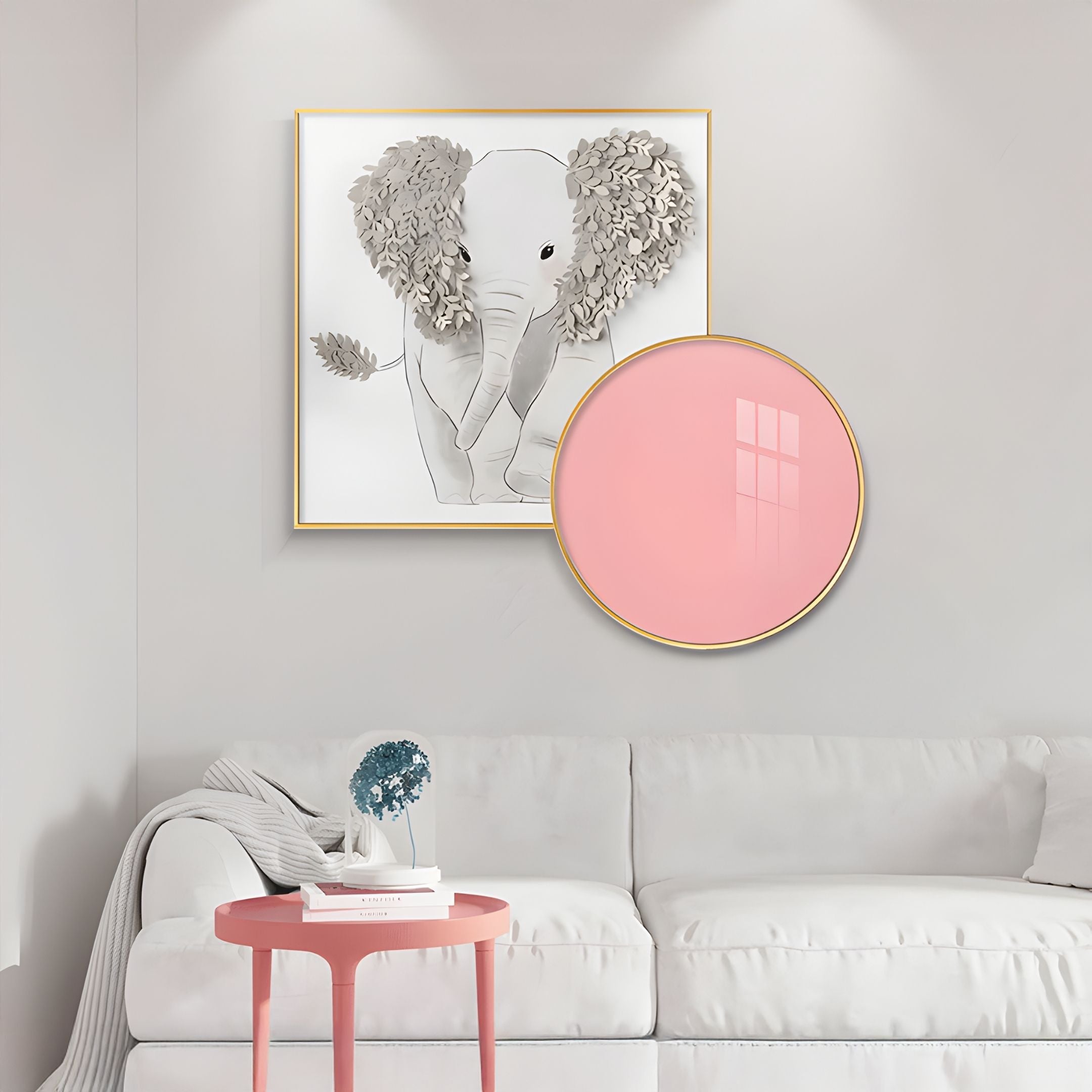 A white sofa with a gray blanket sits against a light wall. Above it hangs Giant Sculptures’ Blossomkin Pink Petal Elephant Kids 3D Wall Art and a large round pink mirror. A small pink side table holds a decorative blue plant.