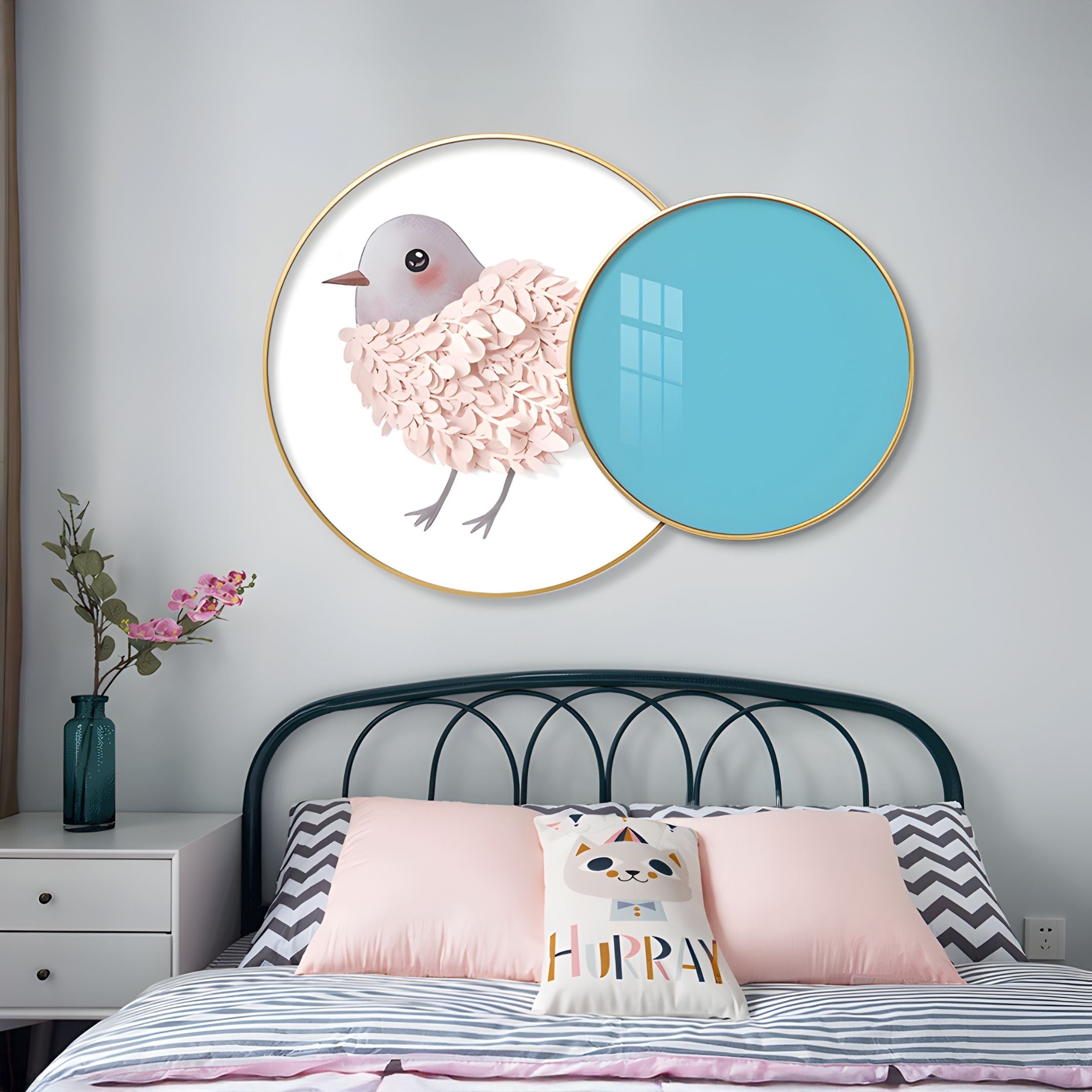 A bedroom with a bed featuring a “HURRAY” cat pillow, zigzag bedspread, flowers on the bedside table, and Blossomkin Blue Petal Bird Kids 3D Wall Art by Giant Sculptures—showing a pink-feathered bird partly covered by a blue circle.