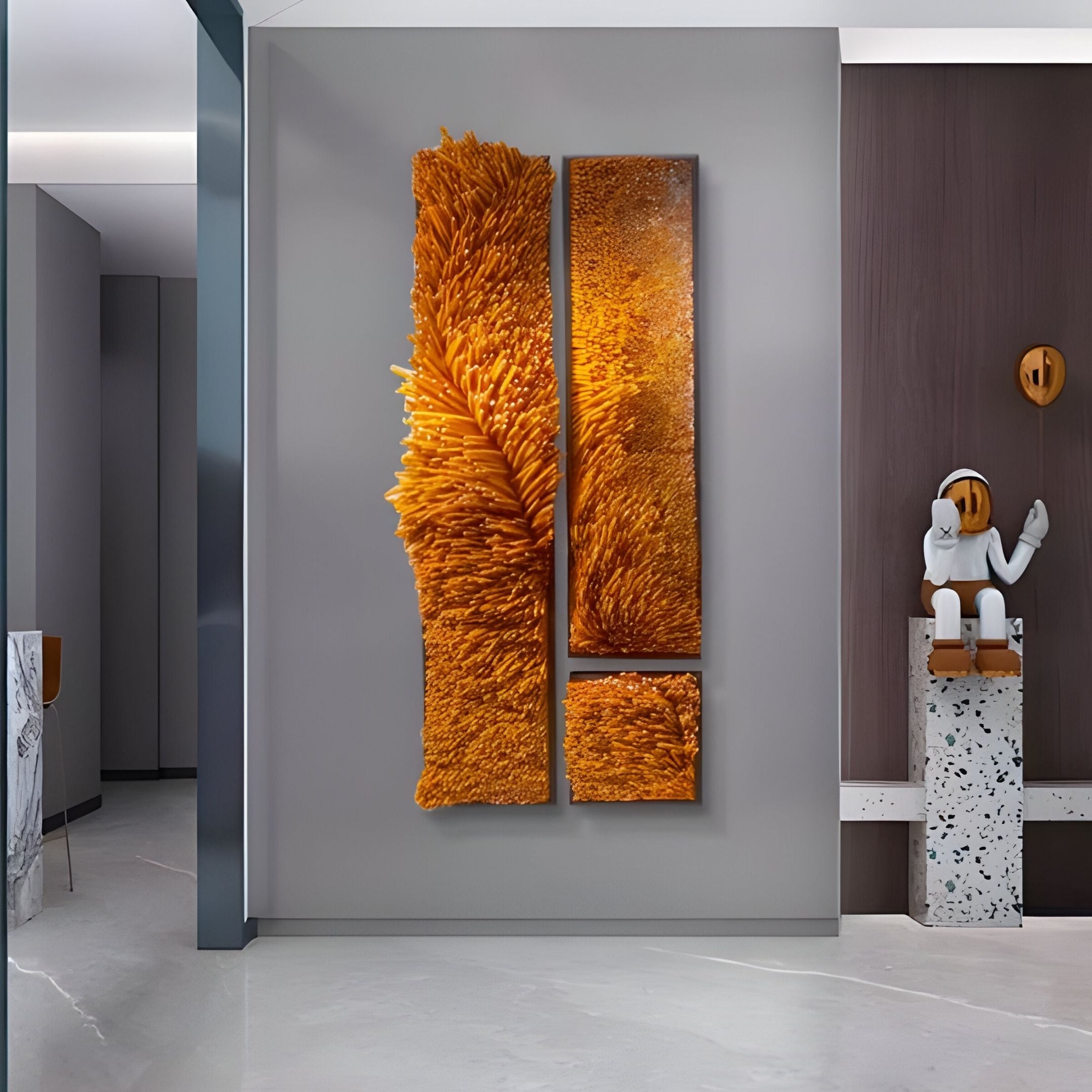A modern interior with a gray wall showcases Giant Sculptures’ Bristella Amber Textured 3-Panel 3D Wall Art. A playful white figurine on a terrazzo pedestal completes the sleek, minimalist sculptural decor.
