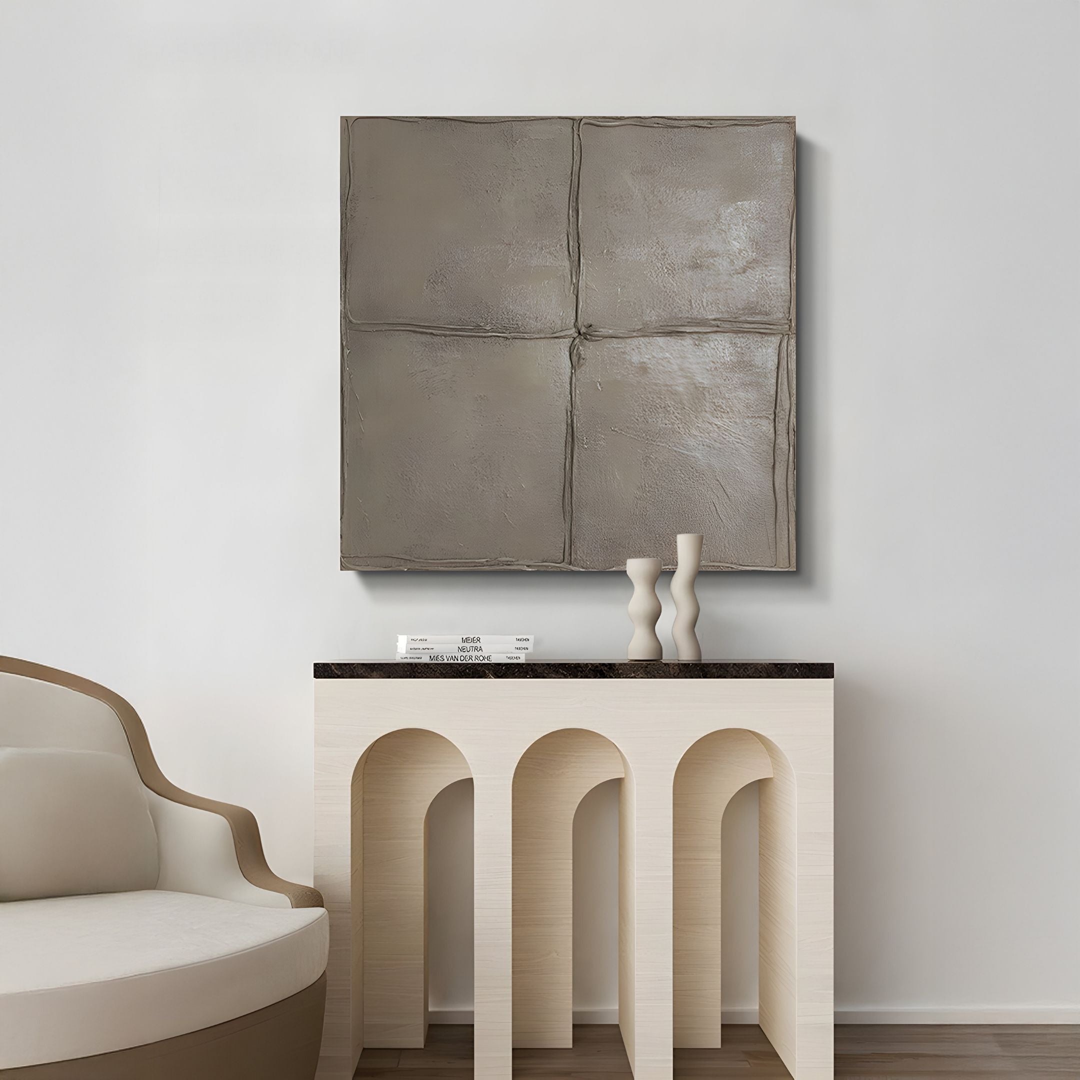 Minimalist living space featuring a curved beige chair, a light console table with arch details, two abstract vases, and four Terracrecta Taupe Painted Textured Square 3D Wall Art panels by Giant Sculptures on a white wall.