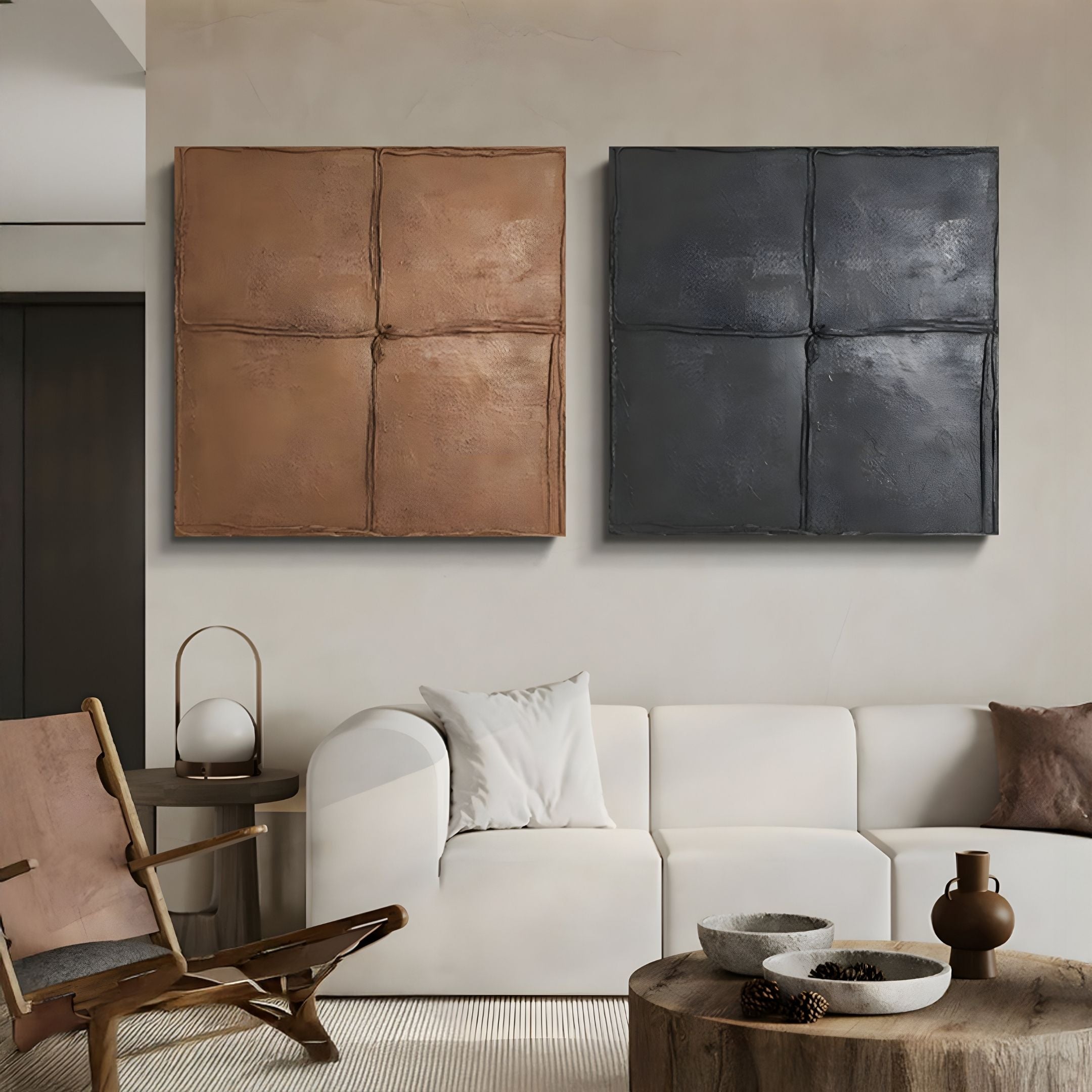 A modern living room with a white sofa, a wooden chair with a brown cushion, and two Giant Sculptures Terracrecta Painted Textured Wall Art pieces—one brown, one charcoal black—displayed side by side above the sofa. A coffee table holds decorative bowls.