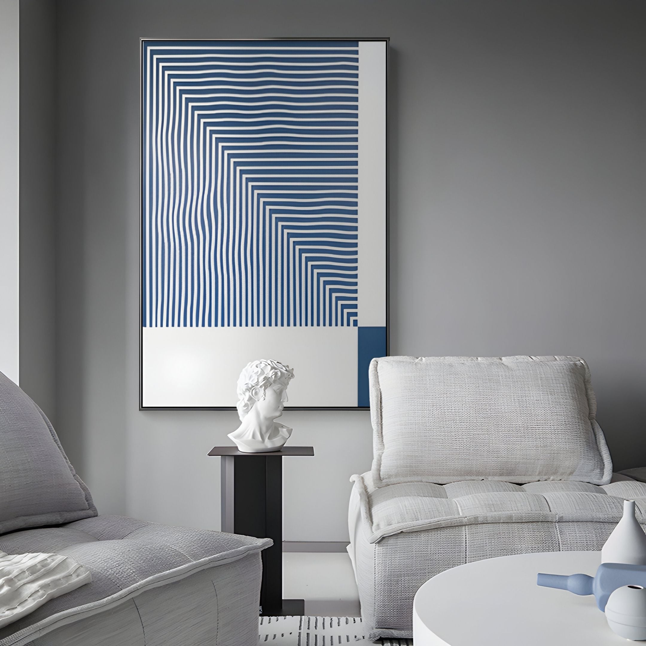 A modern living room with gray walls, white cushioned chairs, a small black table with a white bust, and Giant Sculptures' Linscape Blue Linear Wood Relief 3D Wall Art adding bold blue and white geometric style to the décor.