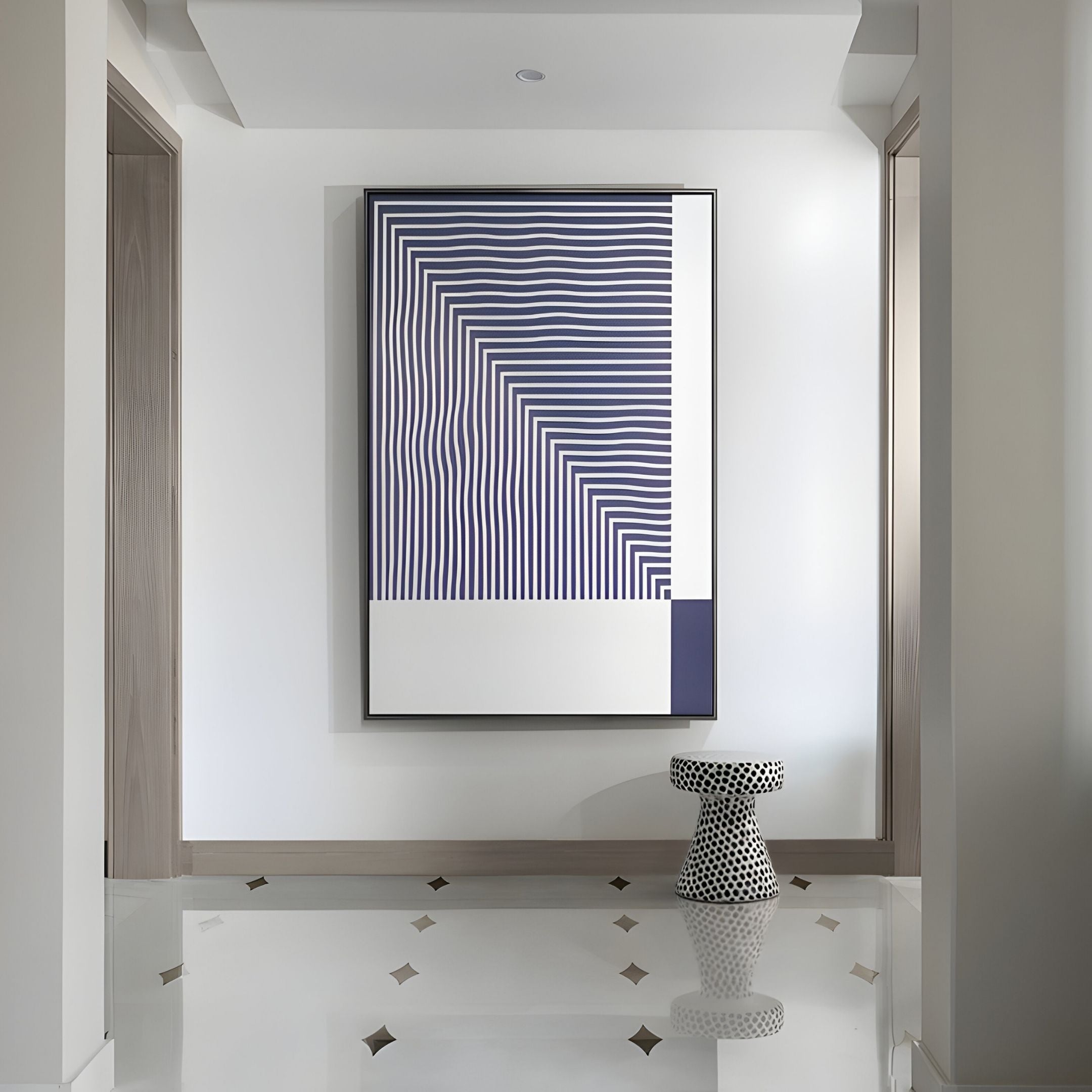 A modern hallway with glossy white floors, neutral walls, and a geometric black-and-white stool features Giant Sculptures’ Linscape Violet Linear Wood Relief 3D Wall Art as a bold statement piece above.