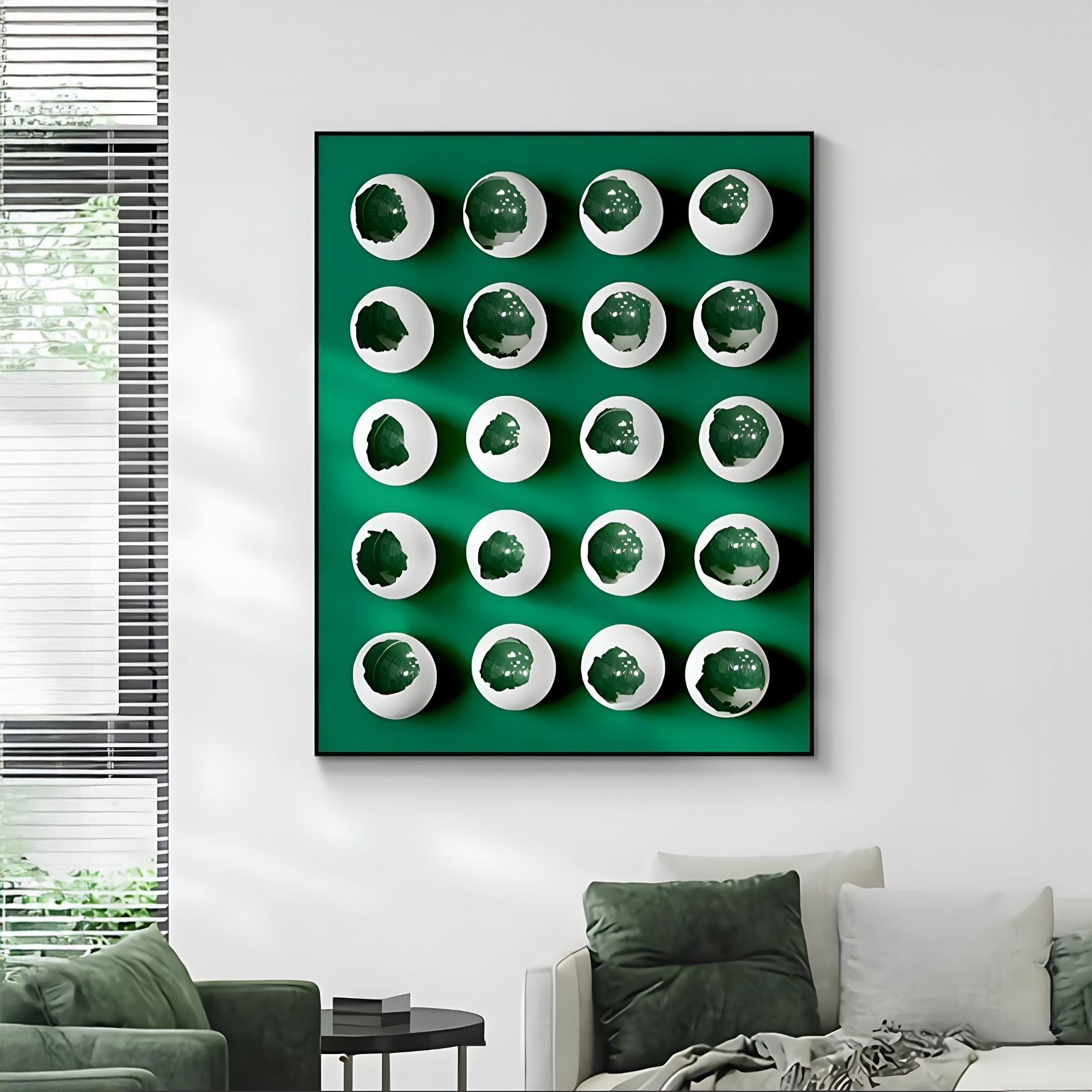 The Orbivelle White & Emerald Patch Sphere Panel 3D Wall Art by Giant Sculptures makes striking emerald wall decor above a modern green and gray sofa, beautifully highlighted by natural light in a bright living room with tall windows.