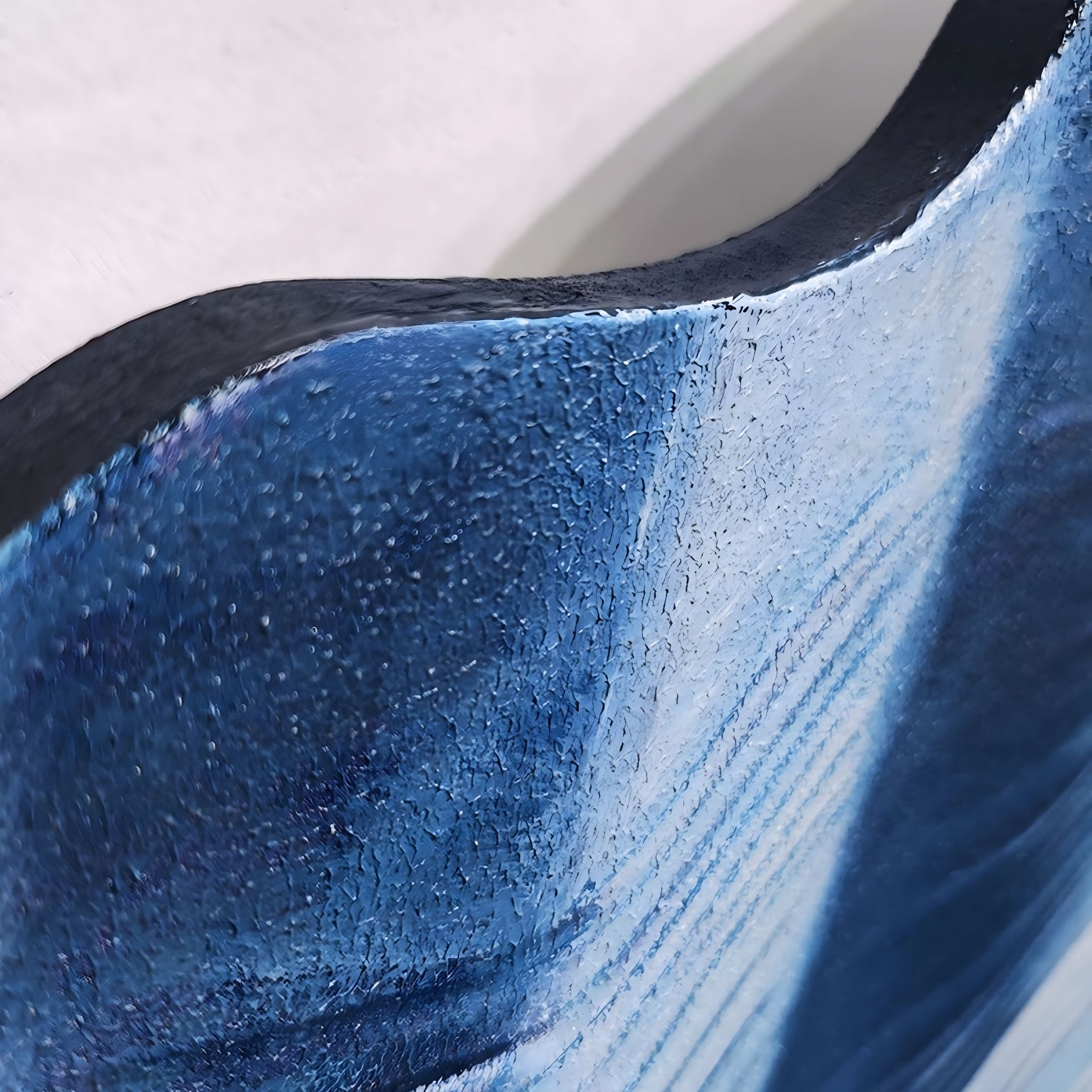 The Vellun Wave Midnight Blue Sculptural 3D Wall Art by Giant Sculptures showcases a textured, curved blue surface with glossy, uneven paint and visible brushstrokes against a light background.