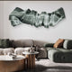 A modern living room with green and gray sofas, a round coffee table, and the Vellun Wave Sage Flow Sculptural 3D Wall Art by Giant Sculptures. The decor is minimal and contemporary.