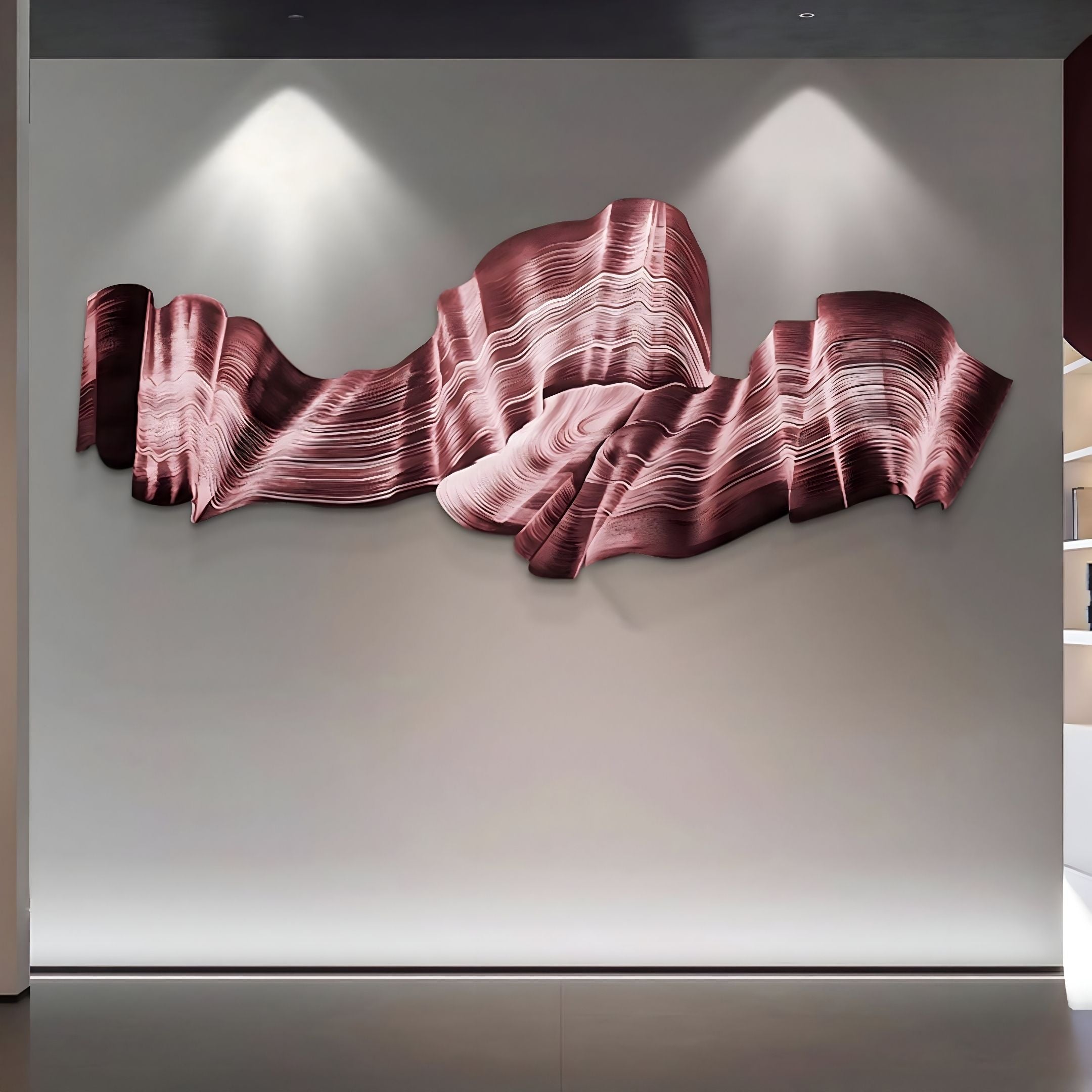 The Vellun Wave Rosewood Sculptural 3D Wall Art by Giant Sculptures features layered, wavy forms in pink and burgundy, mounted on a white wall and highlighted by spotlights in a modern minimalist setting.