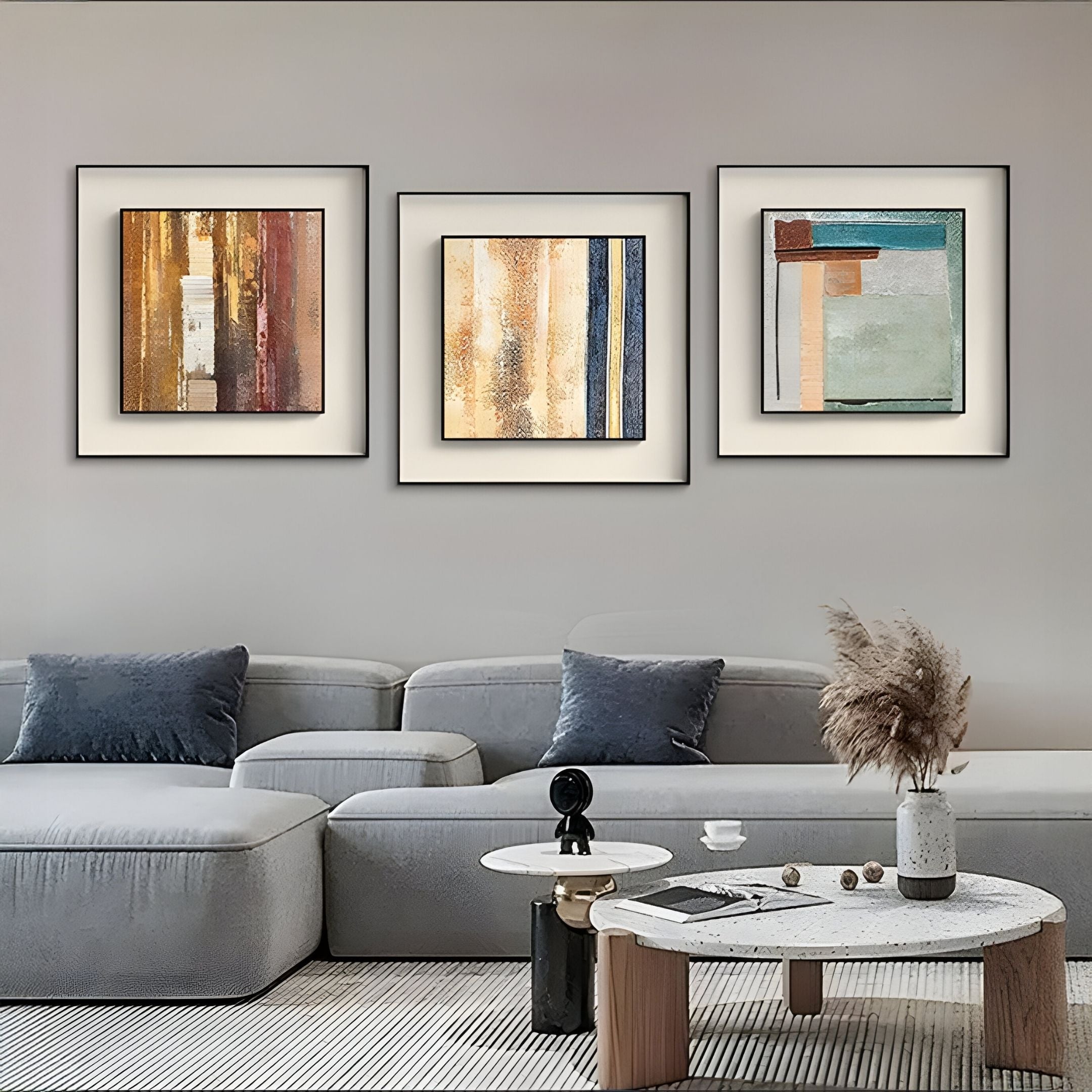 A modern living room with a grey sectional sofa, two round coffee tables, and the Terralume Amber Rust Abstract Textured Framed Wall Art by Giant Sculptures above the sofa. Pampas grass in a vase and earthy decor complete the neutral palette.