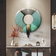 A modern entryway is styled with Giant Sculptures' Vortaryn Verdigris & Steel Circle 3D Wall Art, a vase of orange branches, small sculptures, a pagoda ornament, and a minimalist wall sconce on a neutral wall.