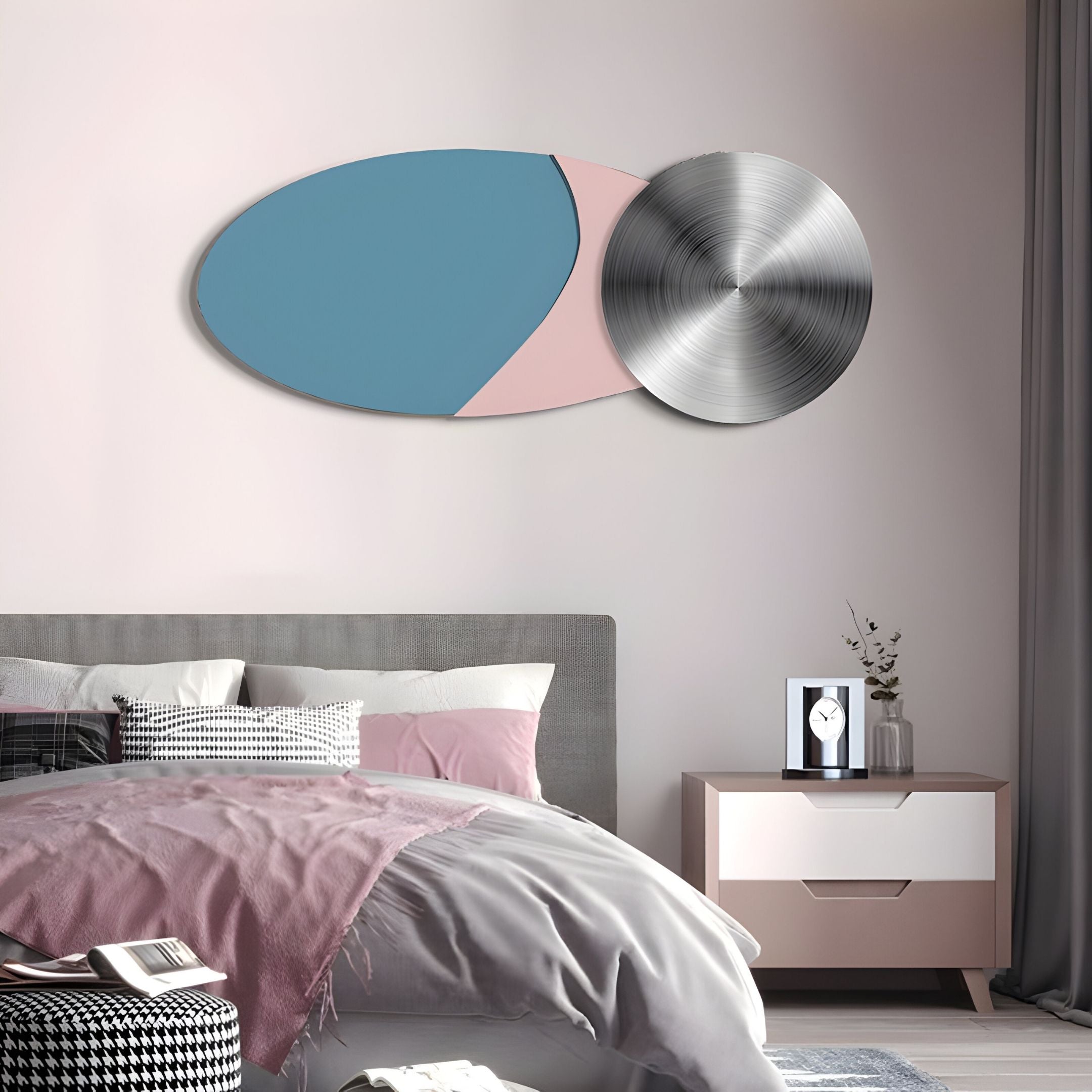 A modern bedroom with gray and pink bedding, a nightstand with a vase and clock, and Giant Sculptures’ Aurelune Blue & Pink Silver Metal Disc 3D Wall Art above the bed against a light-colored wall.