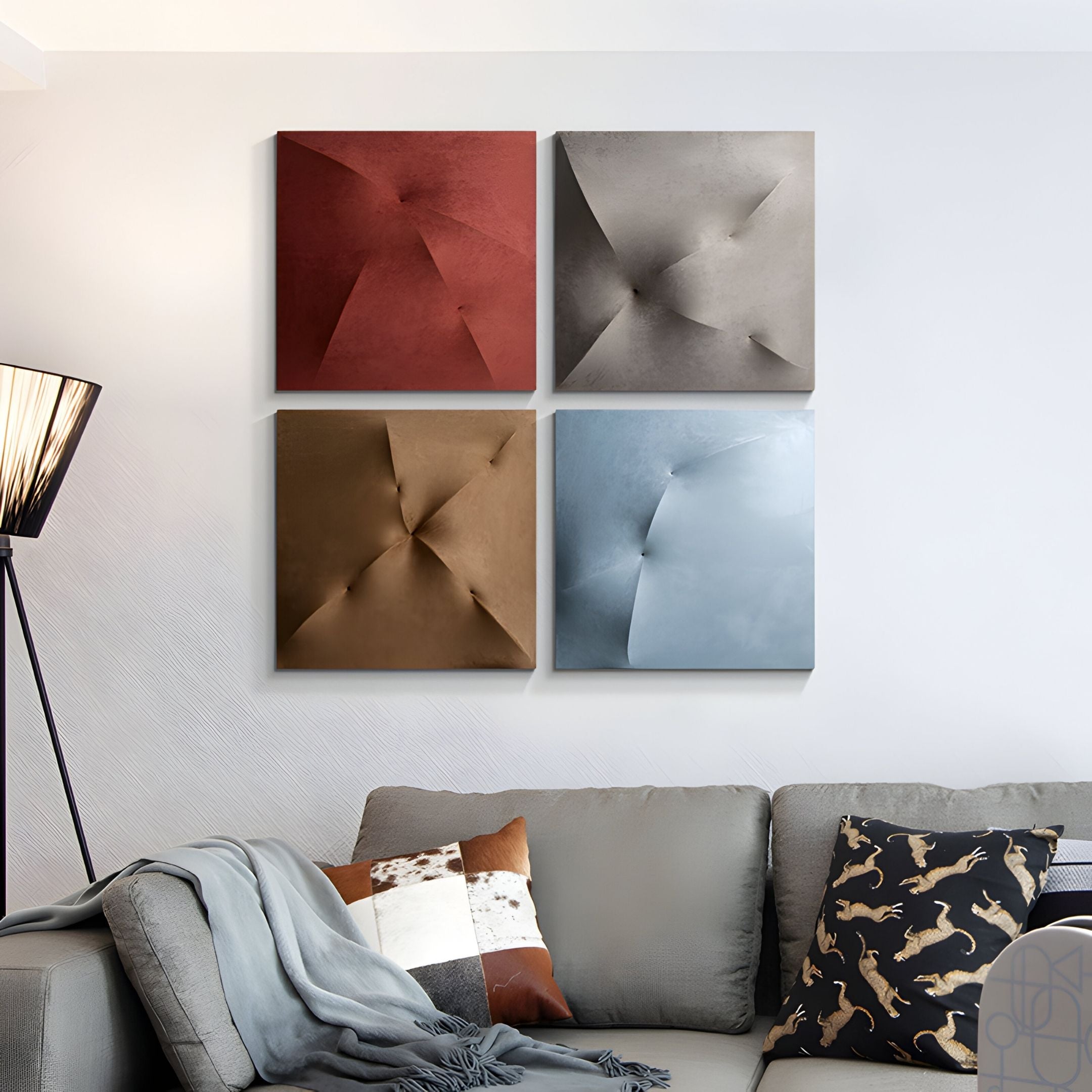 A modern living room features a grey couch, patterned pillows, a throw blanket, a floor lamp, and four square 3D wall art pieces—including the Veylora Ice Blue Folded Texture Fabric 3D Wall Art by Giant Sculptures—above the sofa for added depth.