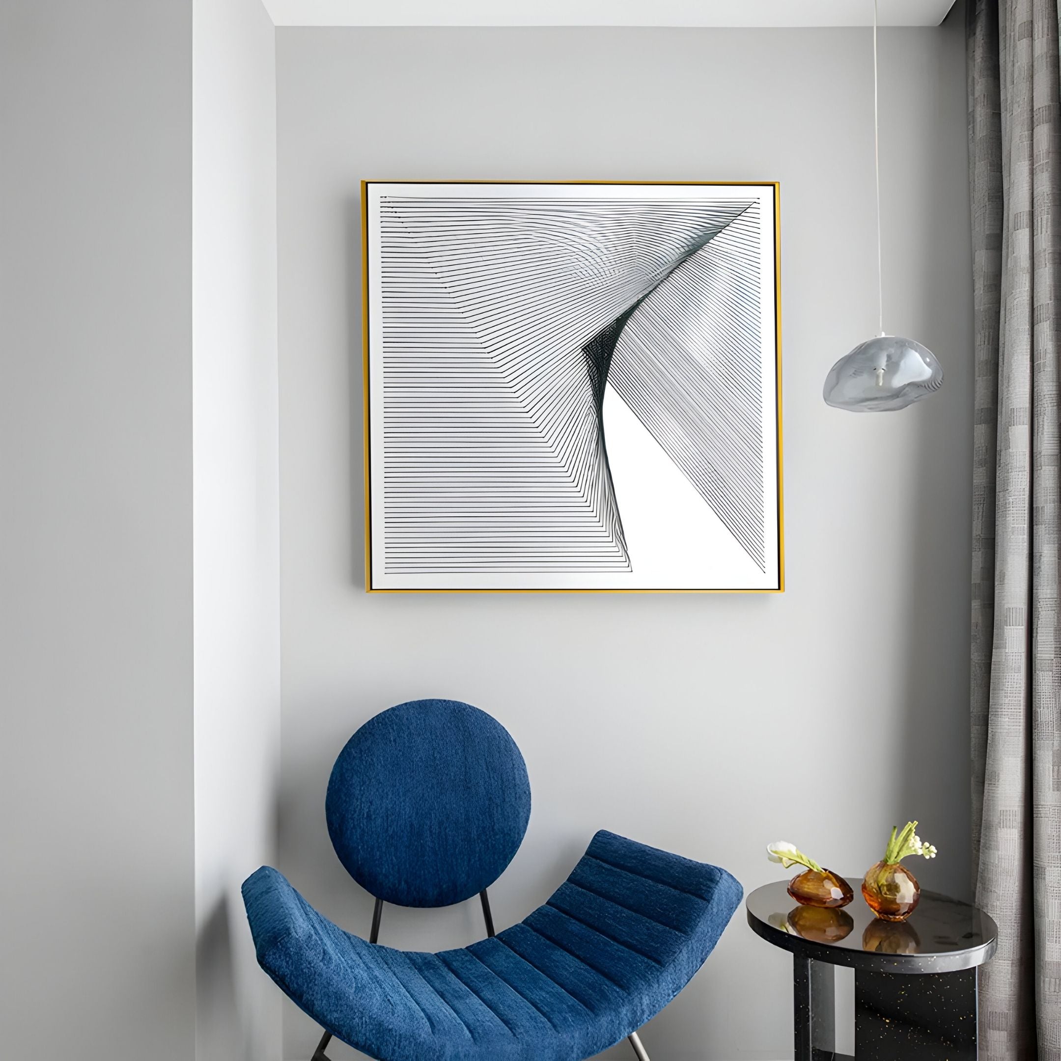 A modern living space features a gray wall with the LineaFlux Deep Teal Thread Warp Geometric 3D Wall Art by Giant Sculptures in a gold frame, a blue round chair, glass table with two vases, and a hanging glass light near window with gray curtains.
