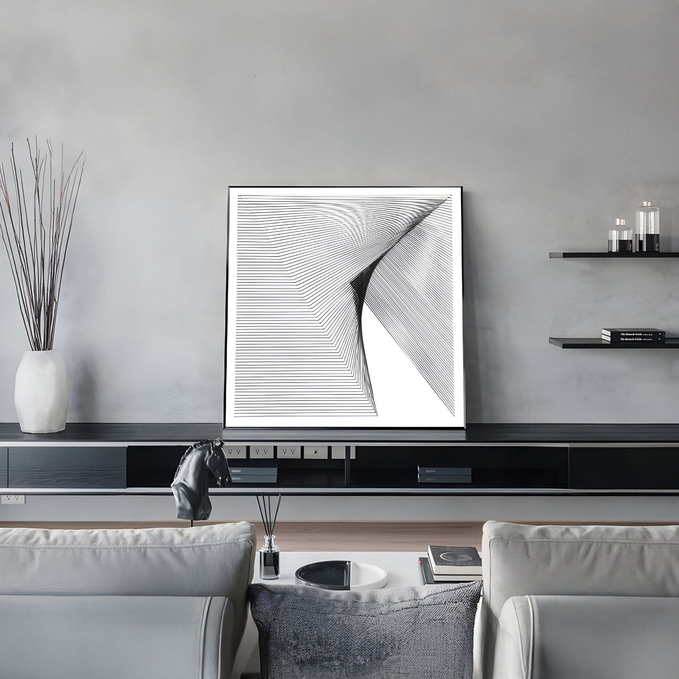 A modern living room with gray walls, the LineaFlux Black Thread Warp Geometric 3D Wall Art by Giant Sculptures above a black console, a vase with tall sticks, floating shelves, and a sofa facing a coffee table.