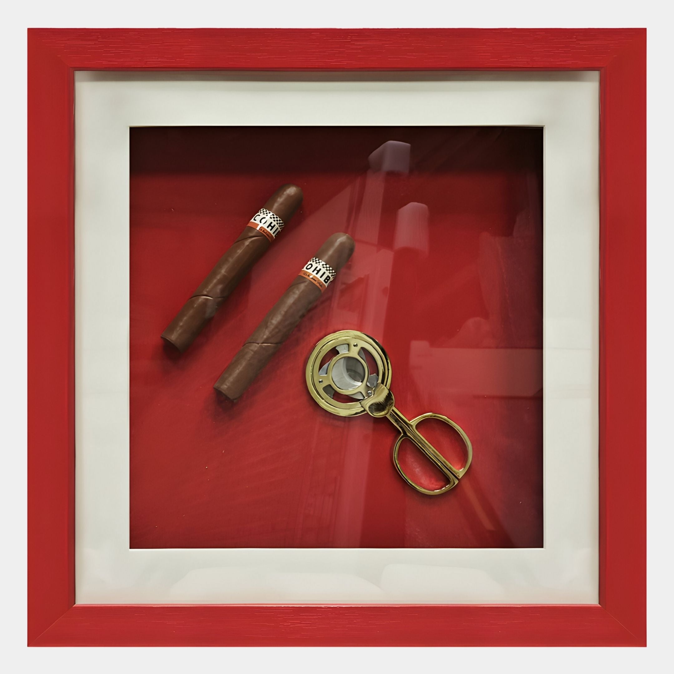 The Cavendro Twin Cigars & Brass Cutter Framed Wall Art by Giant Sculptures features two cigars and a brass cutter on a vivid red background, creating the perfect cigar-themed wall art.