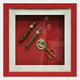 The Cavendro Twin Cigars & Brass Cutter Framed Wall Art by Giant Sculptures features two cigars and a brass cutter on a vivid red background, creating the perfect cigar-themed wall art.