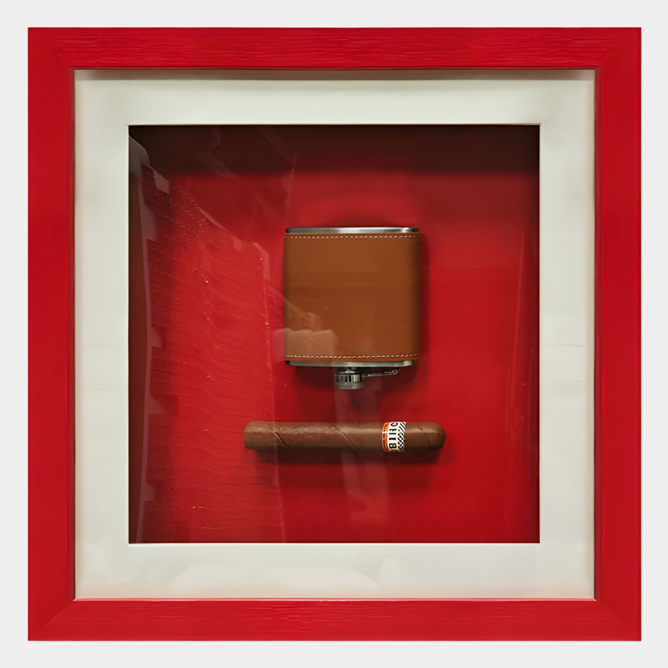 The Cavendro Brown Flask & Cigar Framed Wall Art by Giant Sculptures features a brown flask and cigar in a shadow box with a red background and red-and-white frame, creating striking wall art for your space.