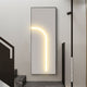 A minimalist interior showcases the Giant Sculptures Luminarch Taupe Curve LED Minimalist Wall Art, its glowing curved light mounted near a staircase with dark steps and modern design accents.