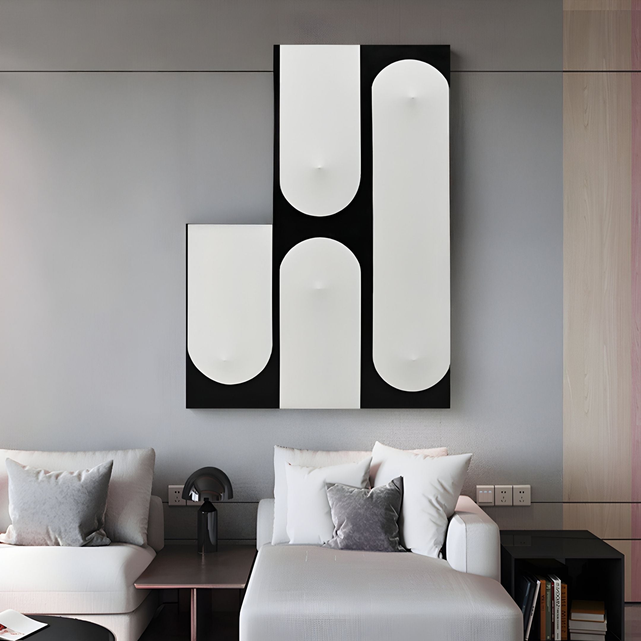 A modern living room with light gray walls, two white sofas with gray pillows, a small side table, and the Curventa Black & White Curved Panel 3D Wall Art by Giant Sculptures mounted above the sofa.