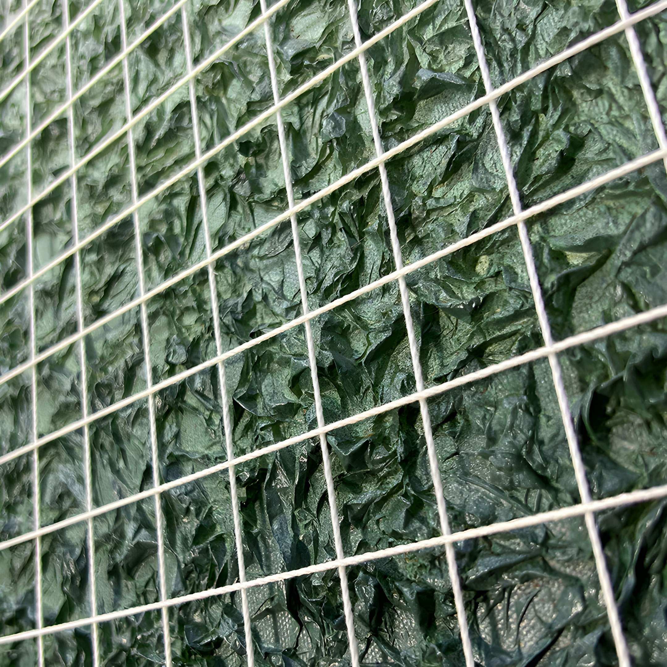 The Gridelle Forest Fade Gradient Grid 3D Paper Wall Art by Giant Sculptures features a textured green surface and white wire grid, resembling crumpled leaves or fabric squares, adding depth and modern flair to contemporary decor.