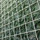 The Gridelle Forest Fade Gradient Grid 3D Paper Wall Art by Giant Sculptures features a textured green surface and white wire grid, resembling crumpled leaves or fabric squares, adding depth and modern flair to contemporary decor.
