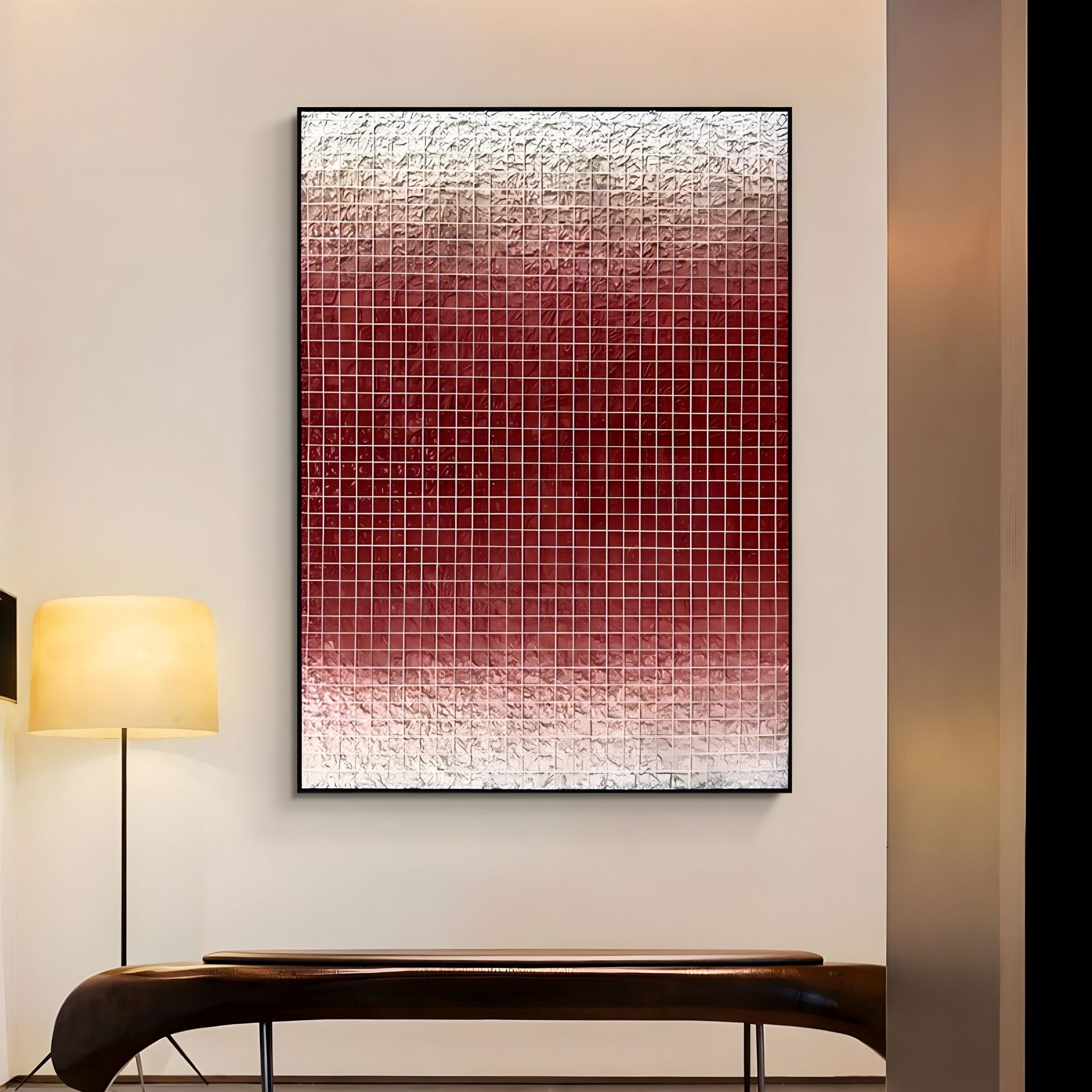 The Gridelle Crimson Fade Gradient Grid 3D Paper Wall Art by Giant Sculptures, featuring small red squares fading to white, hangs above a dark wooden bench on a light wall. A floor lamp with a round yellow shade adds inviting warmth nearby.